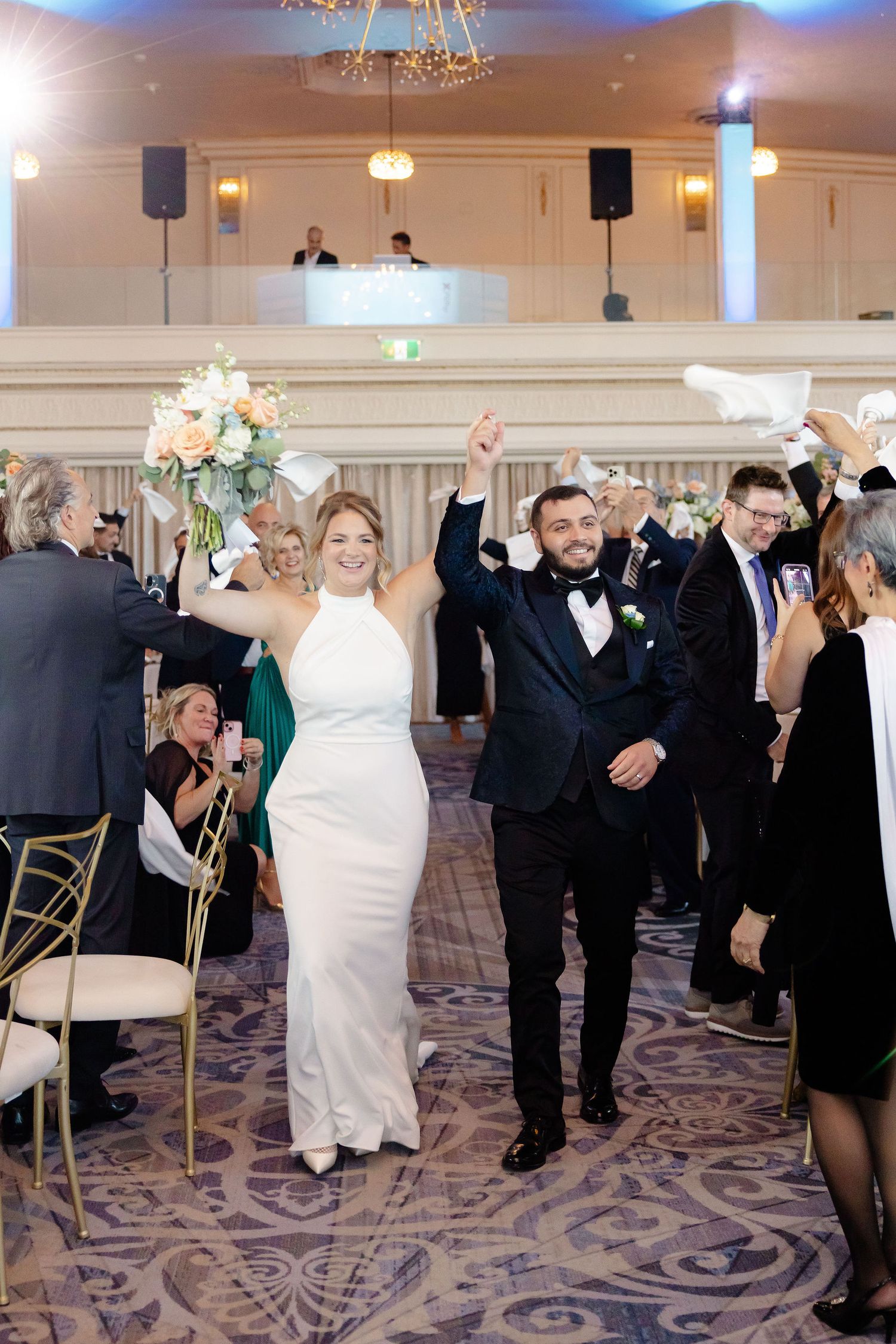 Wedding reception dance floor filled with guests celebrating in a ballroom with patterned carpet.