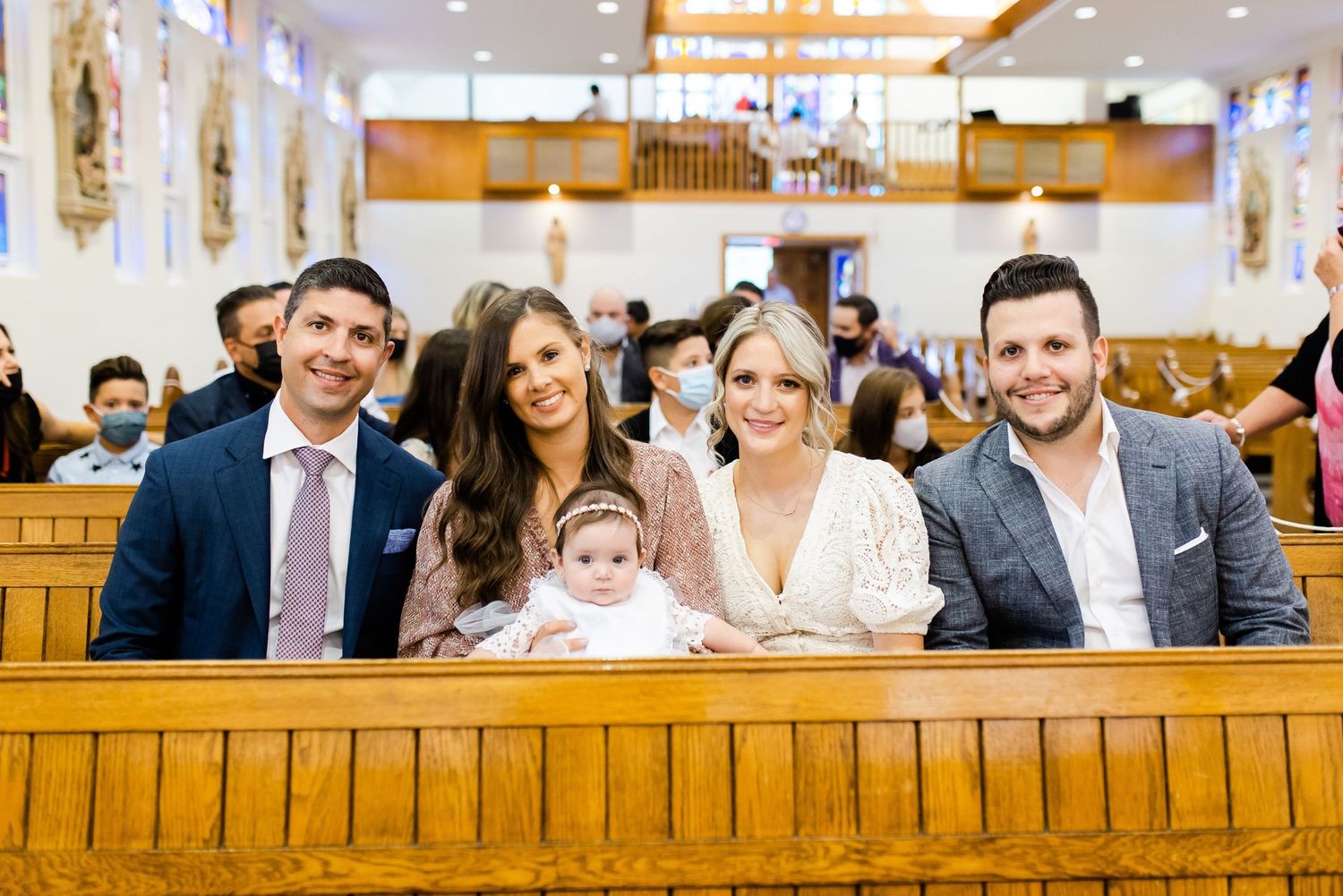 A family sitting together in a wooden church pew during a special ceremony.