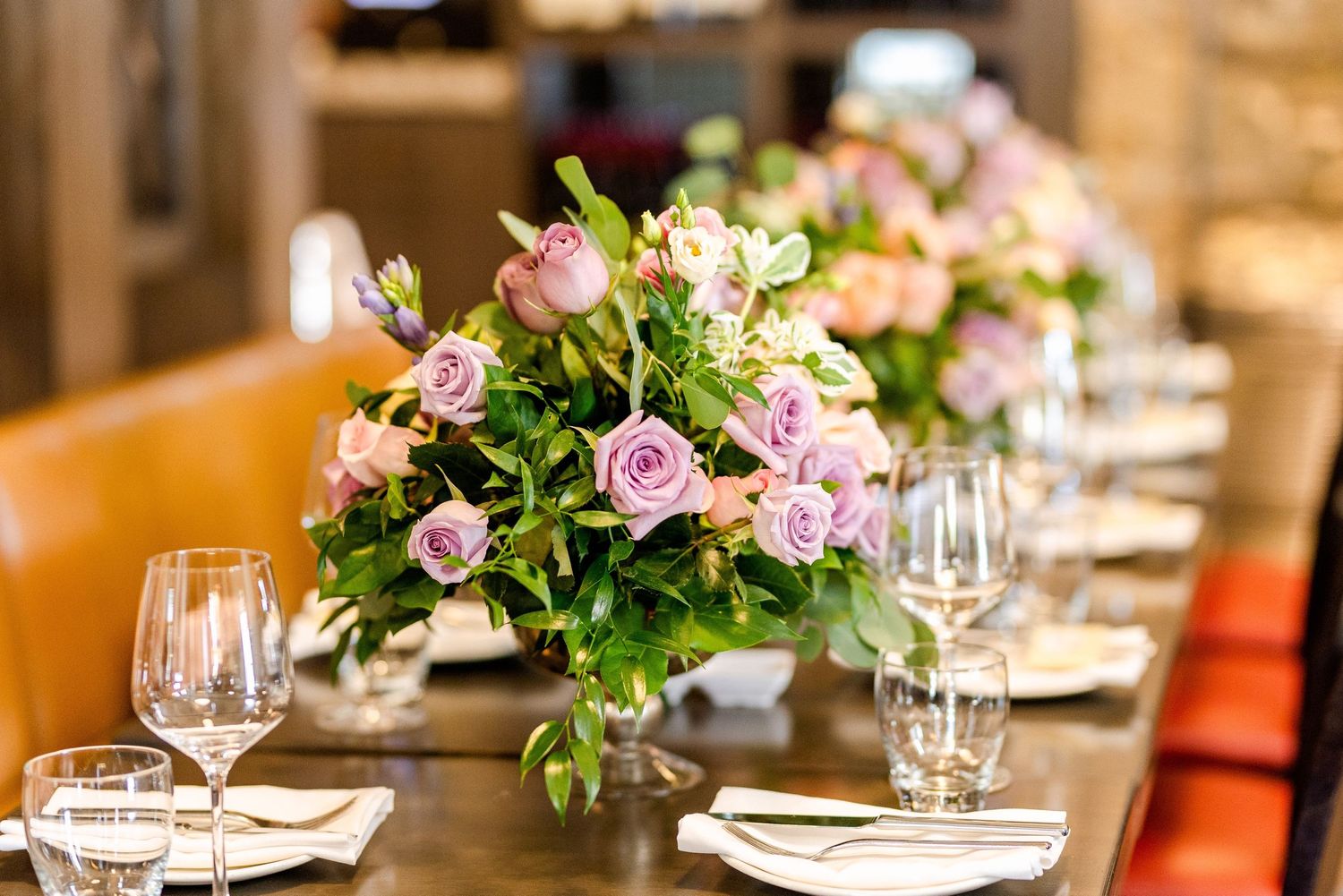Elegant table setting with pink rose centerpiece and wine glasses in upscale restaurant.