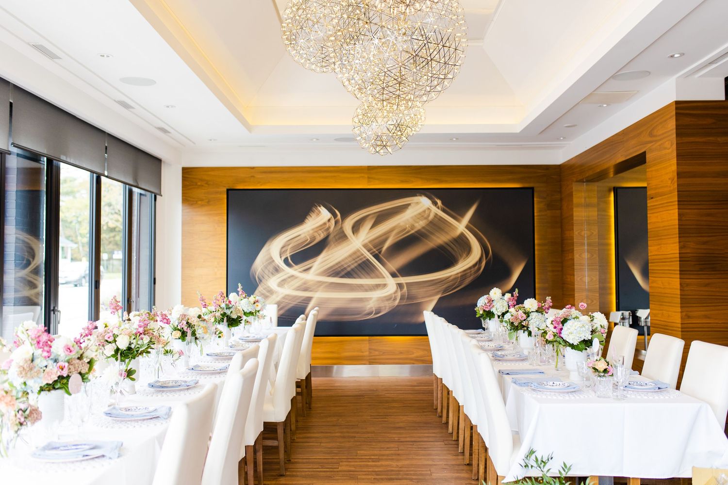 Elegant wedding reception setup with long tables and modern wall art in a bright dining room.