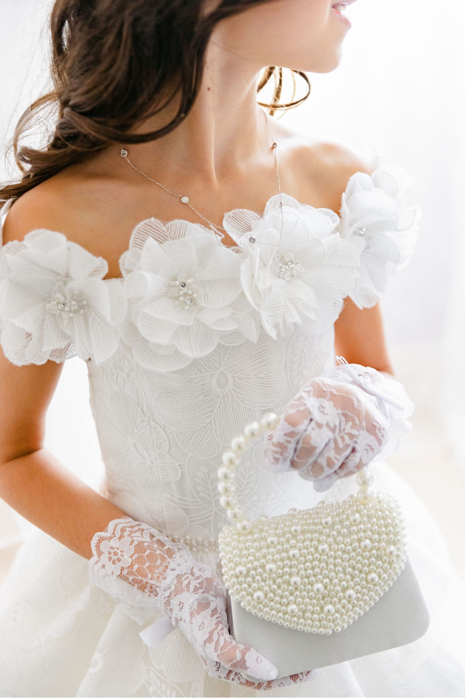 Elegant bridal accessories including lace gloves and a pearl-covered heart-shaped purse with floral dress details.