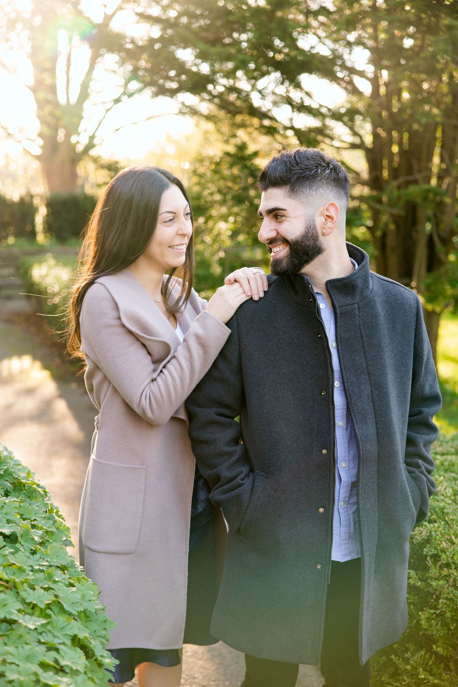 Couple sharing a joyful moment in golden hour sunlight wearing coordinated outerwear.