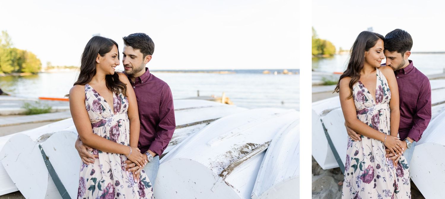 Couple shares intimate moments against white canoes at the waterfront.