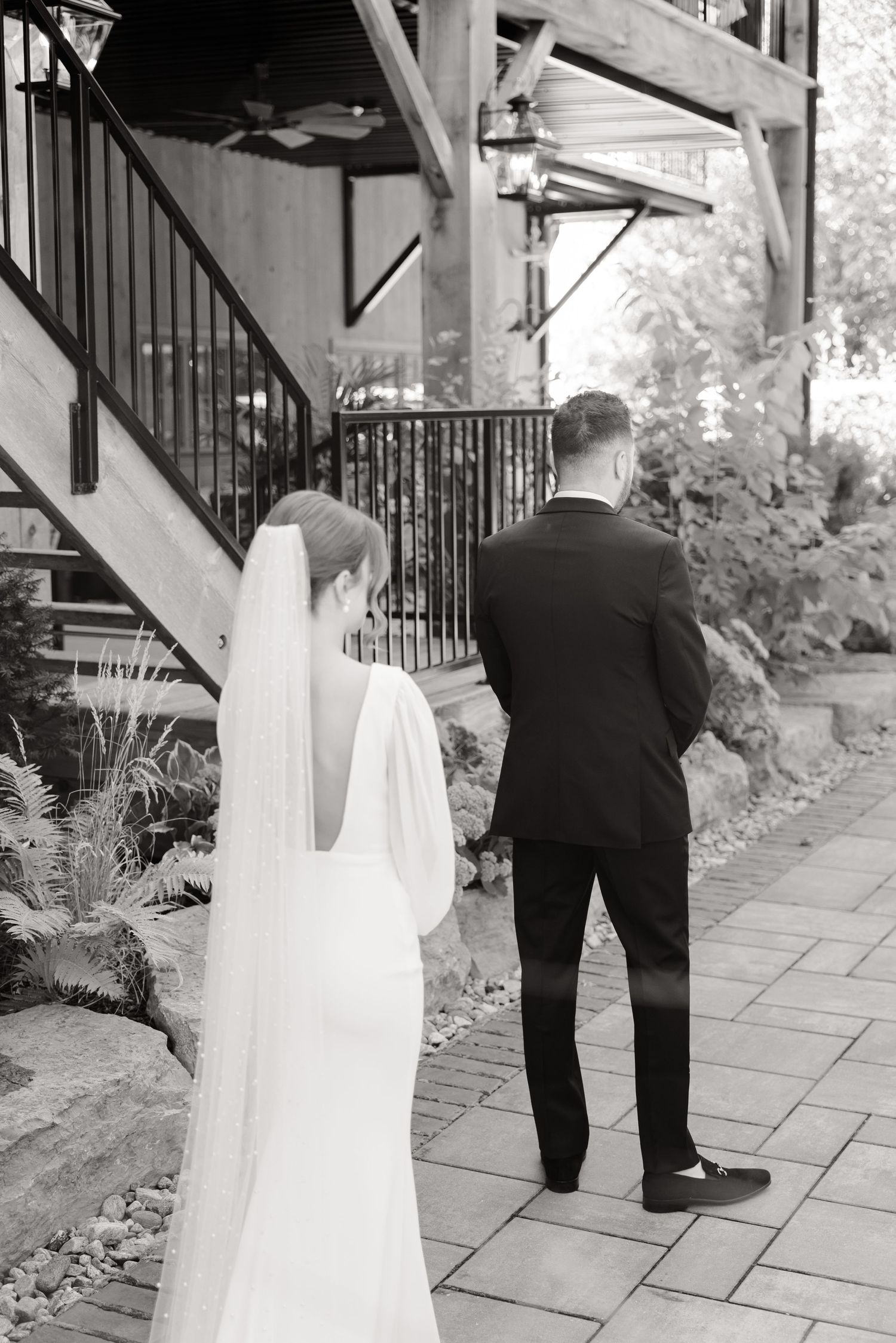 Black and white photo of a couple during their first look moment on a stone patio.