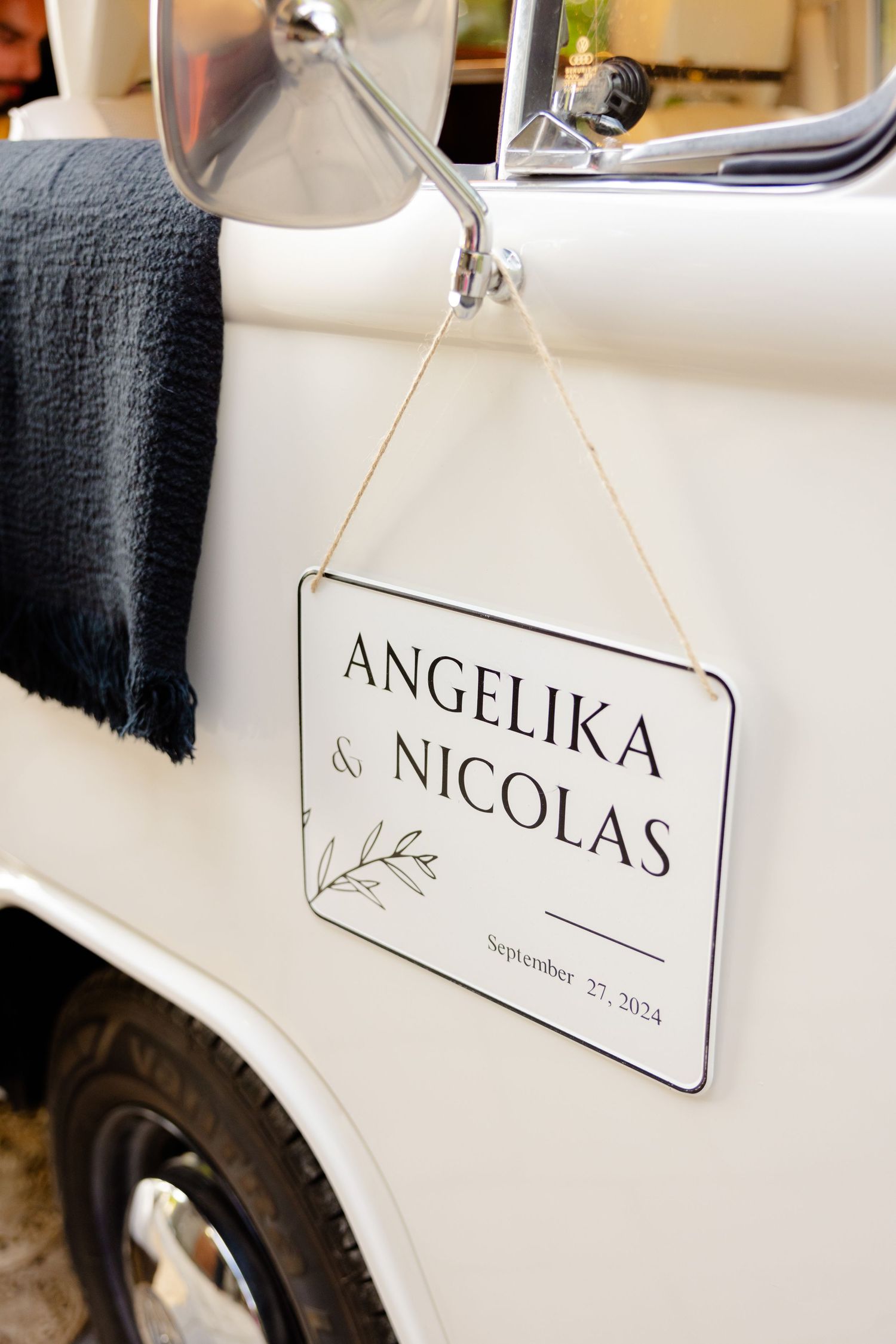 Wedding sign with names and date hanging on white vintage vehicle.