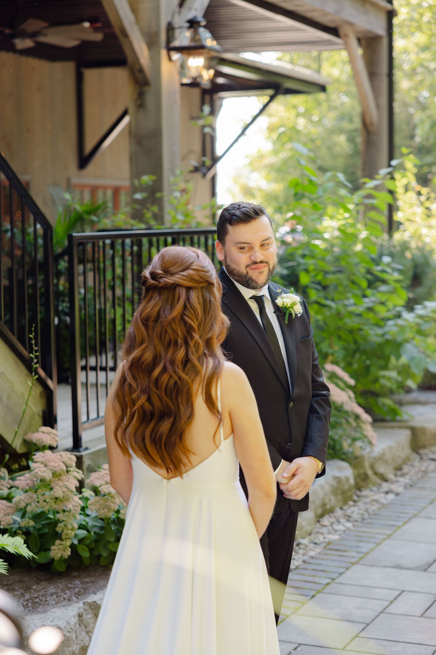 Intimate first look moment between couple on stone path with garden backdrop.