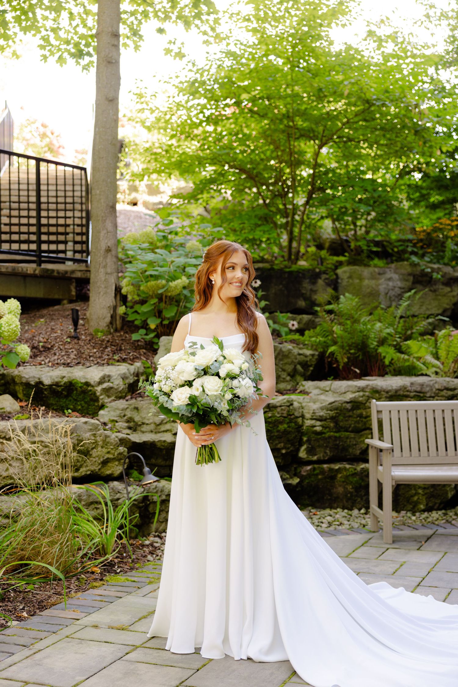 Full-length bridal portrait showcasing a flowing white gown in a garden setting.