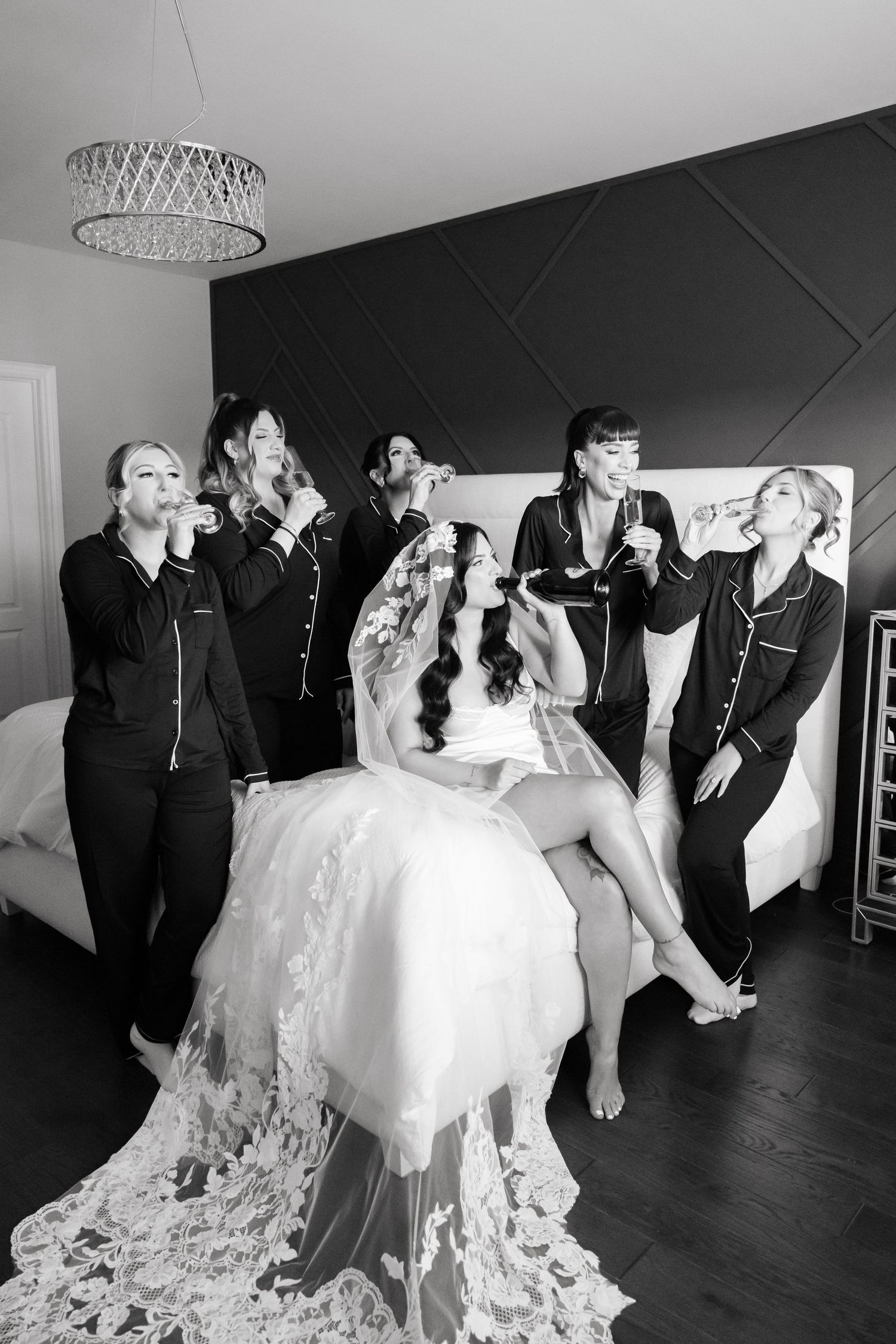 Black and white photo of bridal party drinking champagne in matching sleepwear.