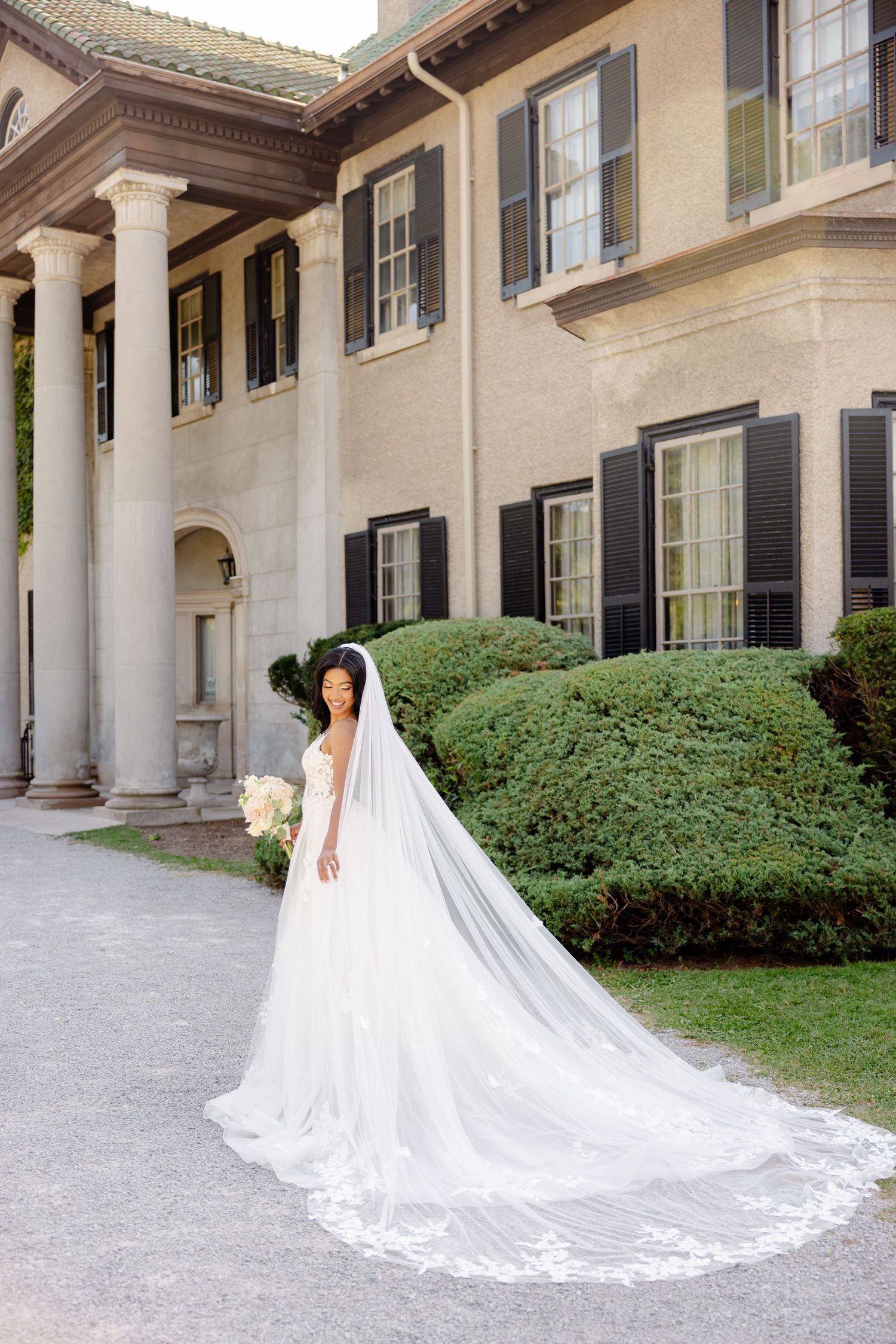 Elegant bridal portrait featuring long lace-trimmed veil against classic architecture.