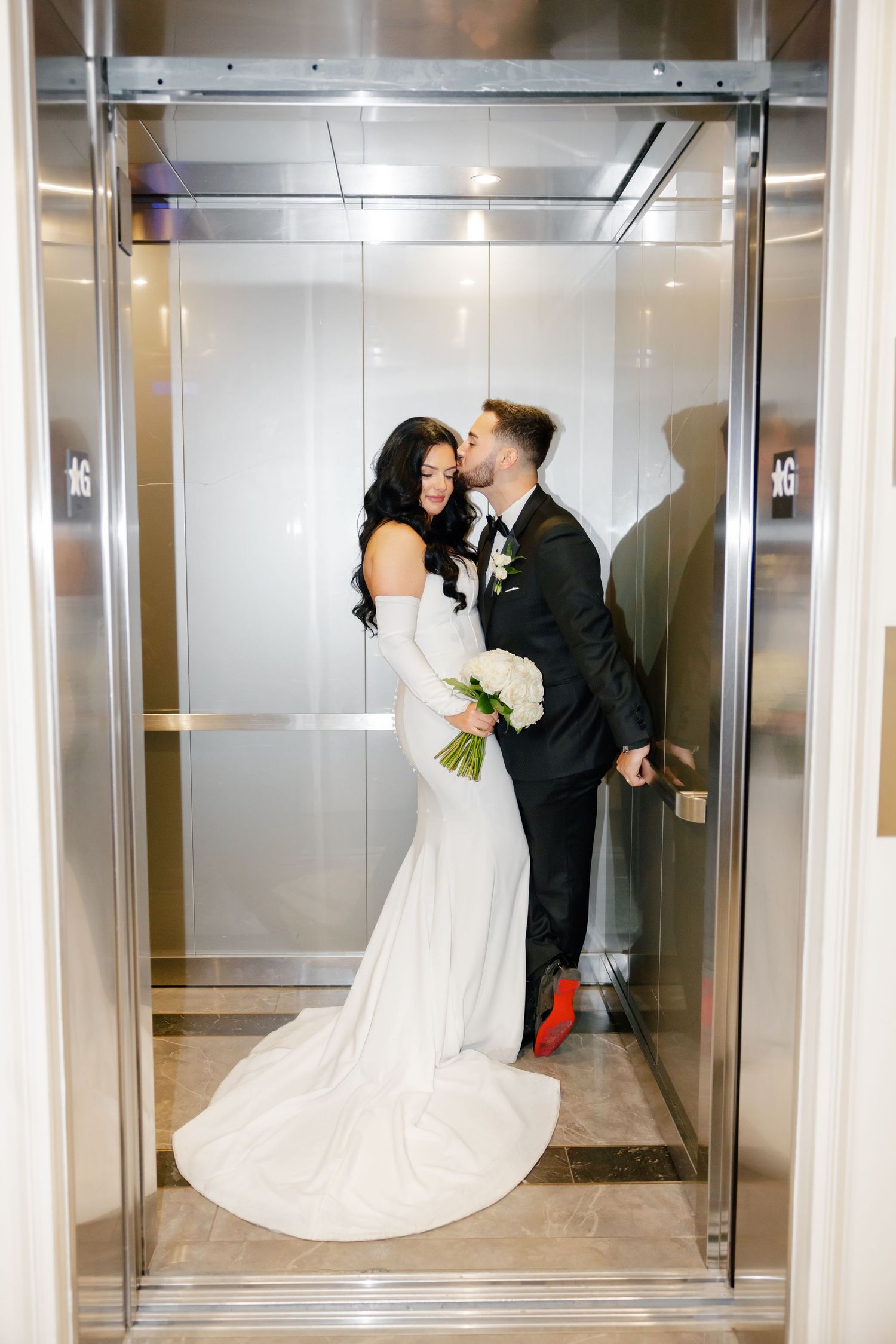 Intimate elevator wedding photo with bride's dress train flowing beautifully.