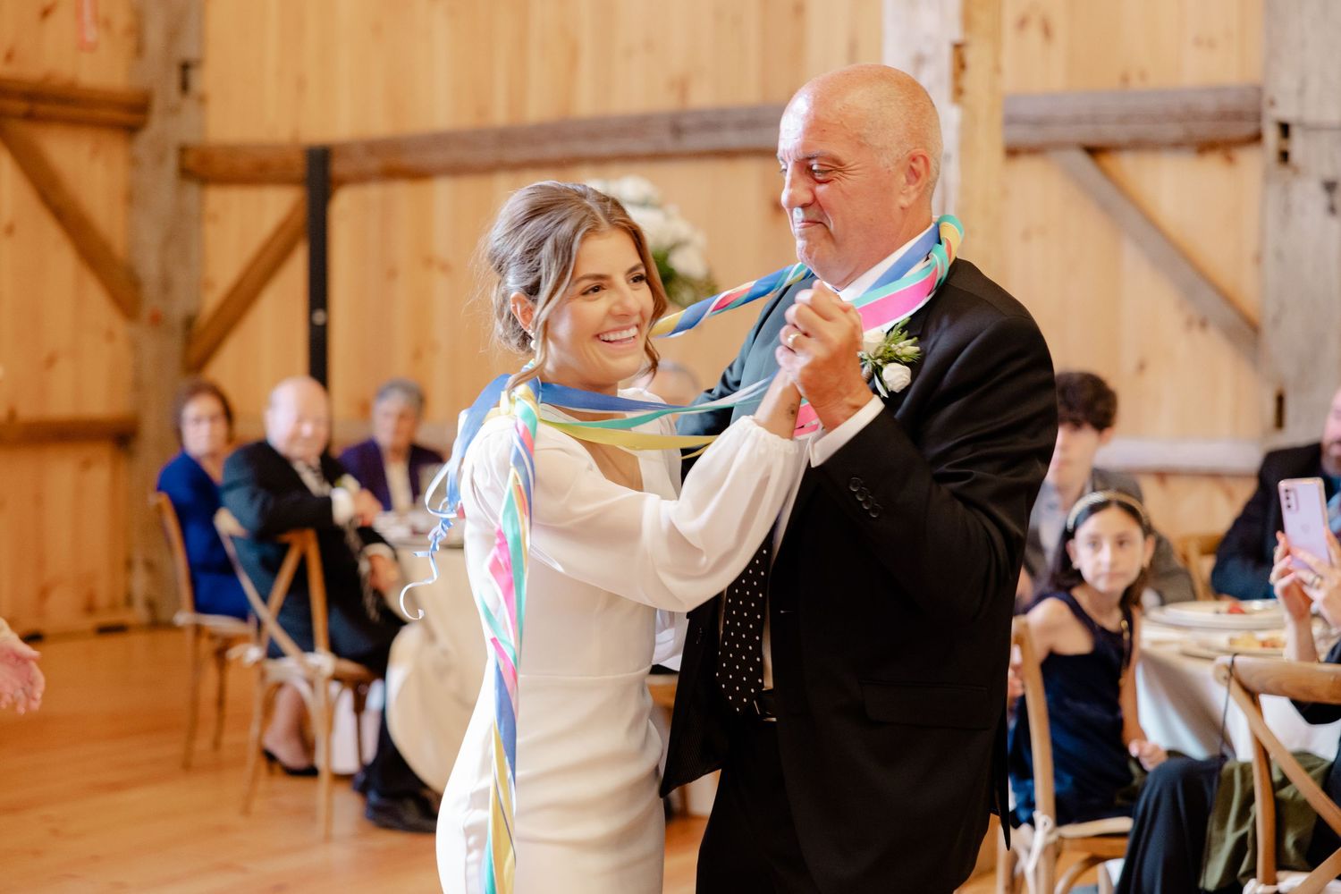 Dancing couple illuminated by natural light in rustic barn wedding venue.