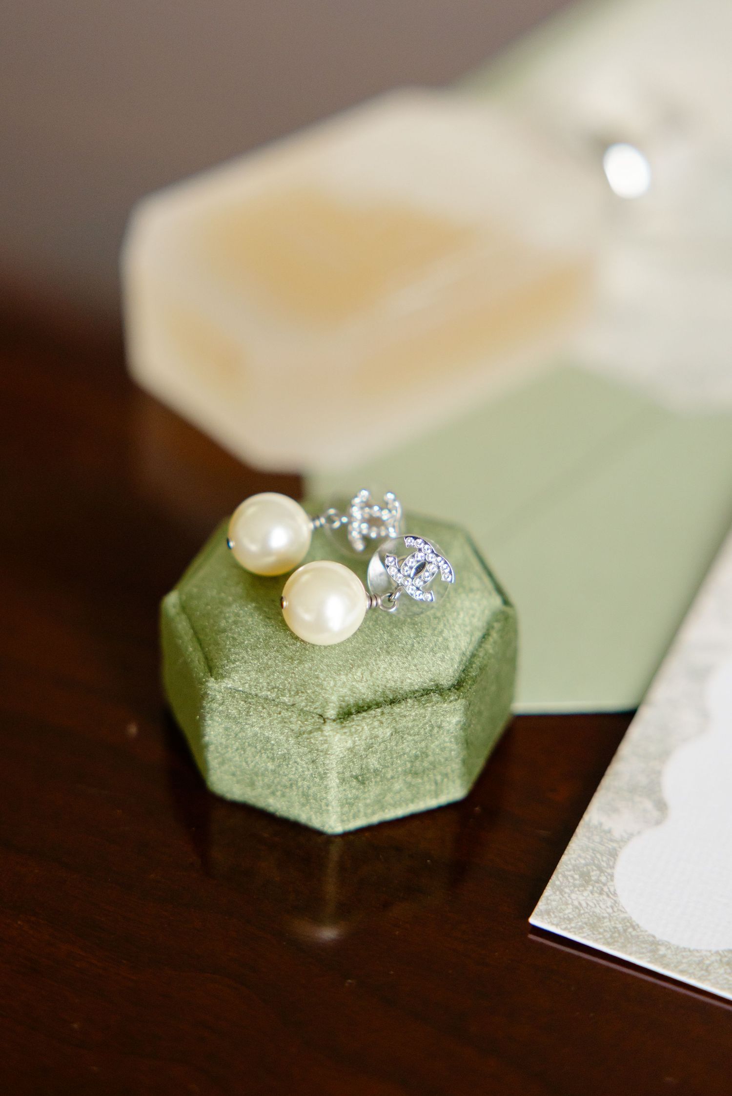 Pearl and diamond engagement rings rest on a mint green velvet ring box in a collection of detail shots.