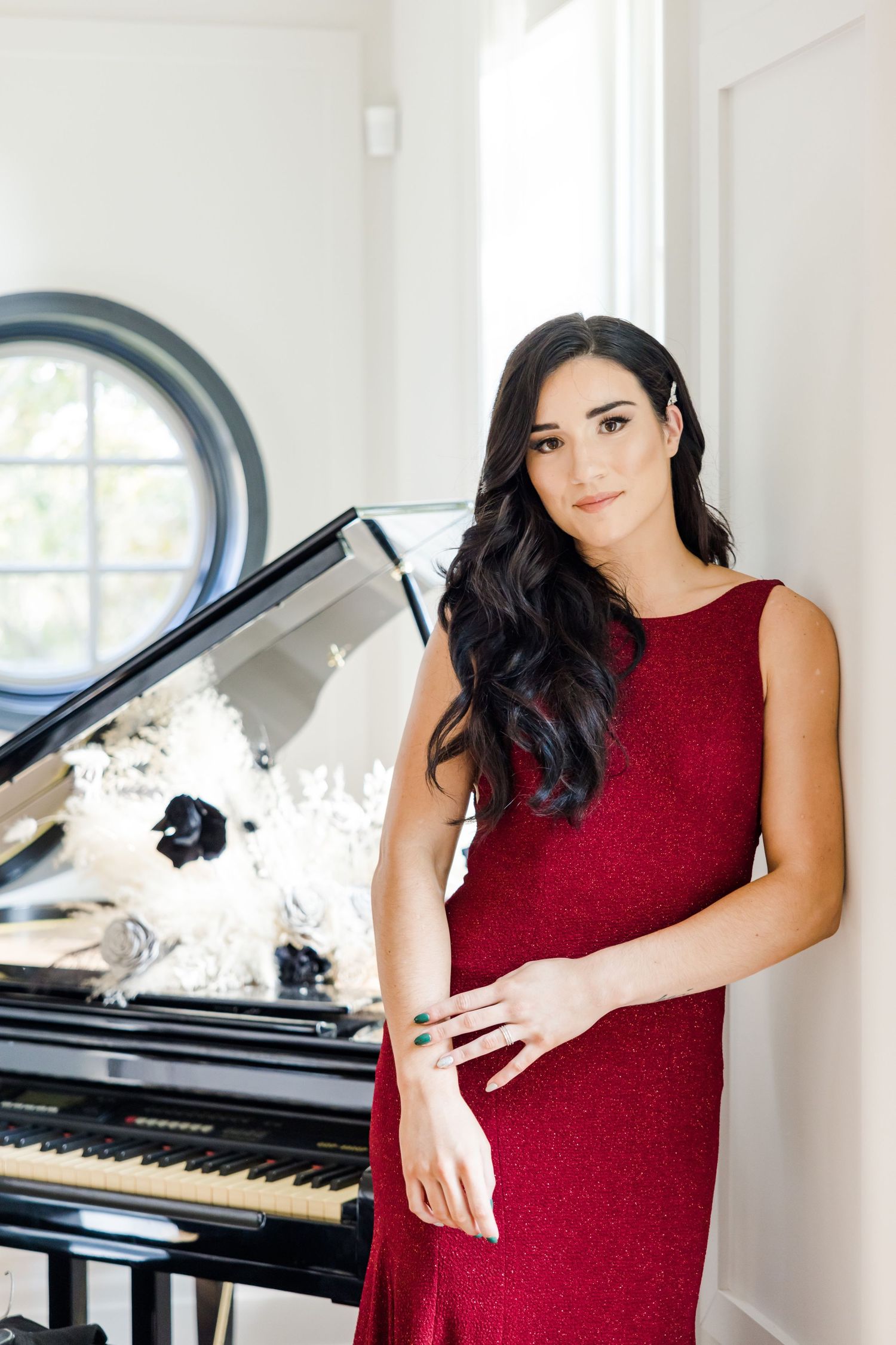 Formal portrait next to grand piano featuring sleek red evening gown and elegant interior.