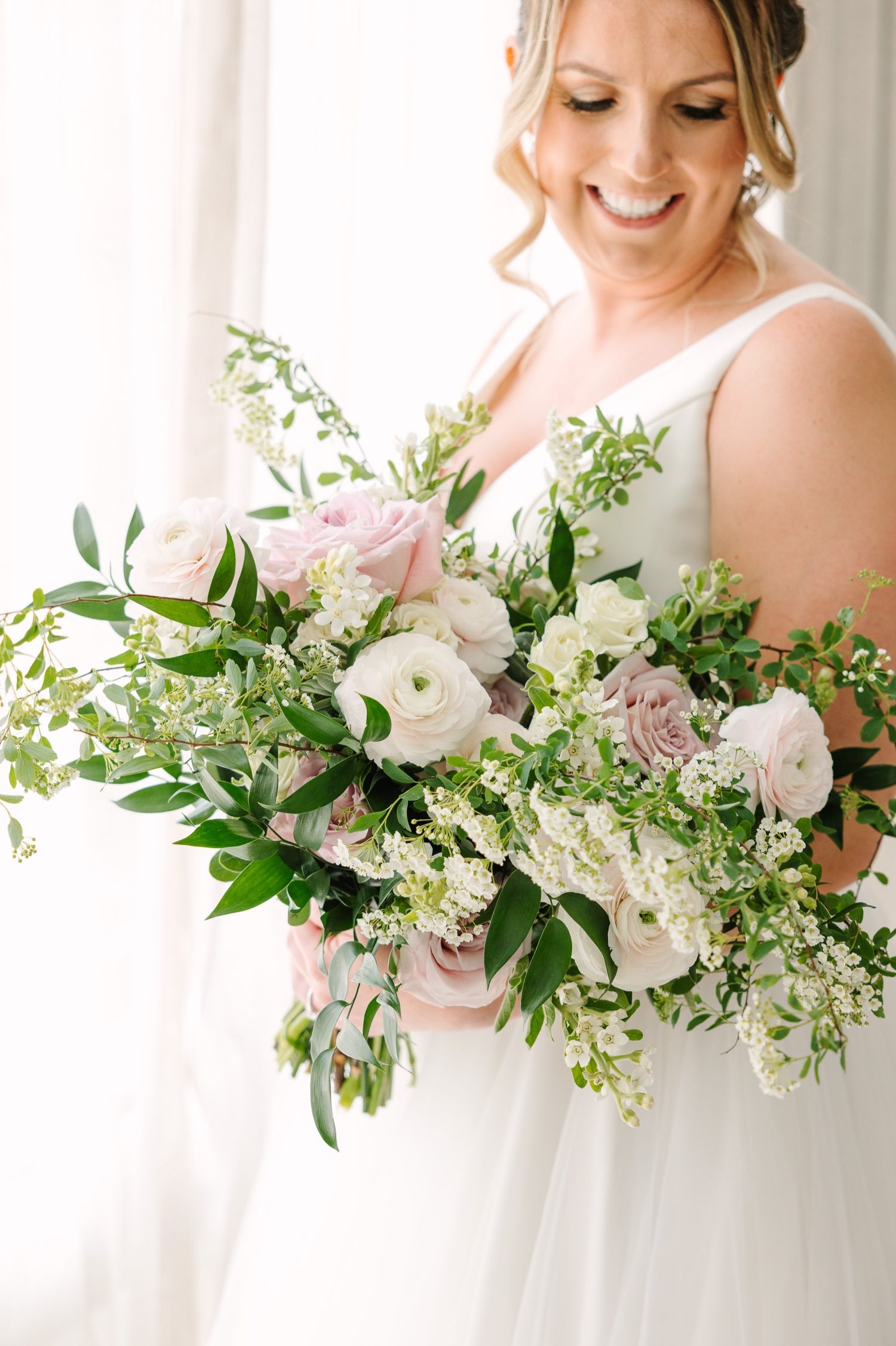 Close-up of romantic bridal bouquet with white roses, pink blooms and cascading greenery.