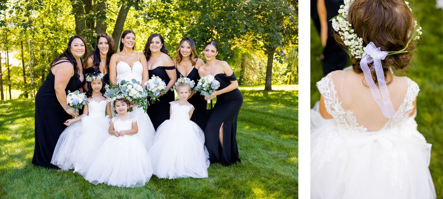 A wedding party in white dresses and black gowns poses together on a sunny lawn.