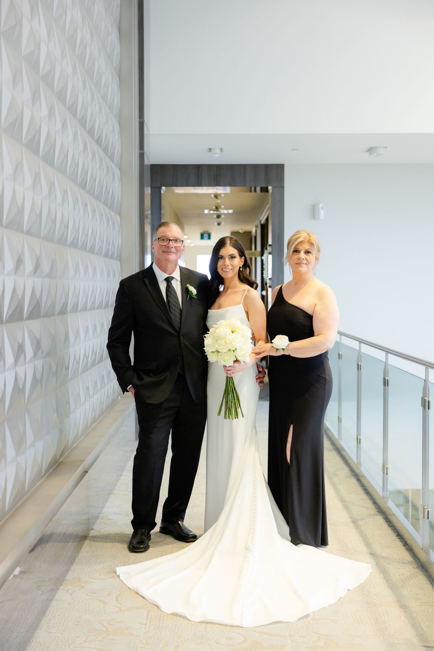 Wedding party poses in modern hallway with geometric white wall details.