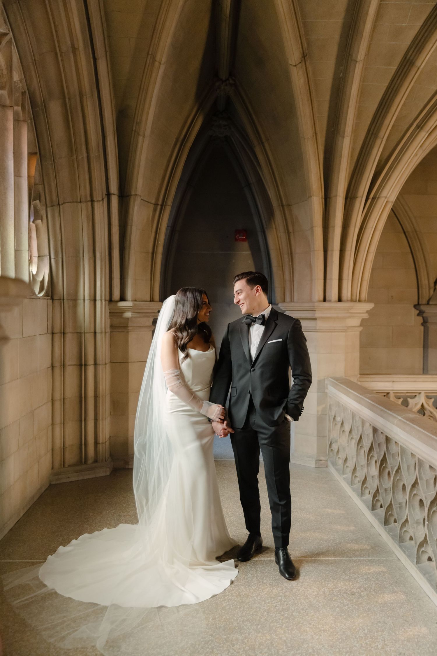 A tender moment between newlyweds in an elegant gothic corridor with vaulted ceilings.
