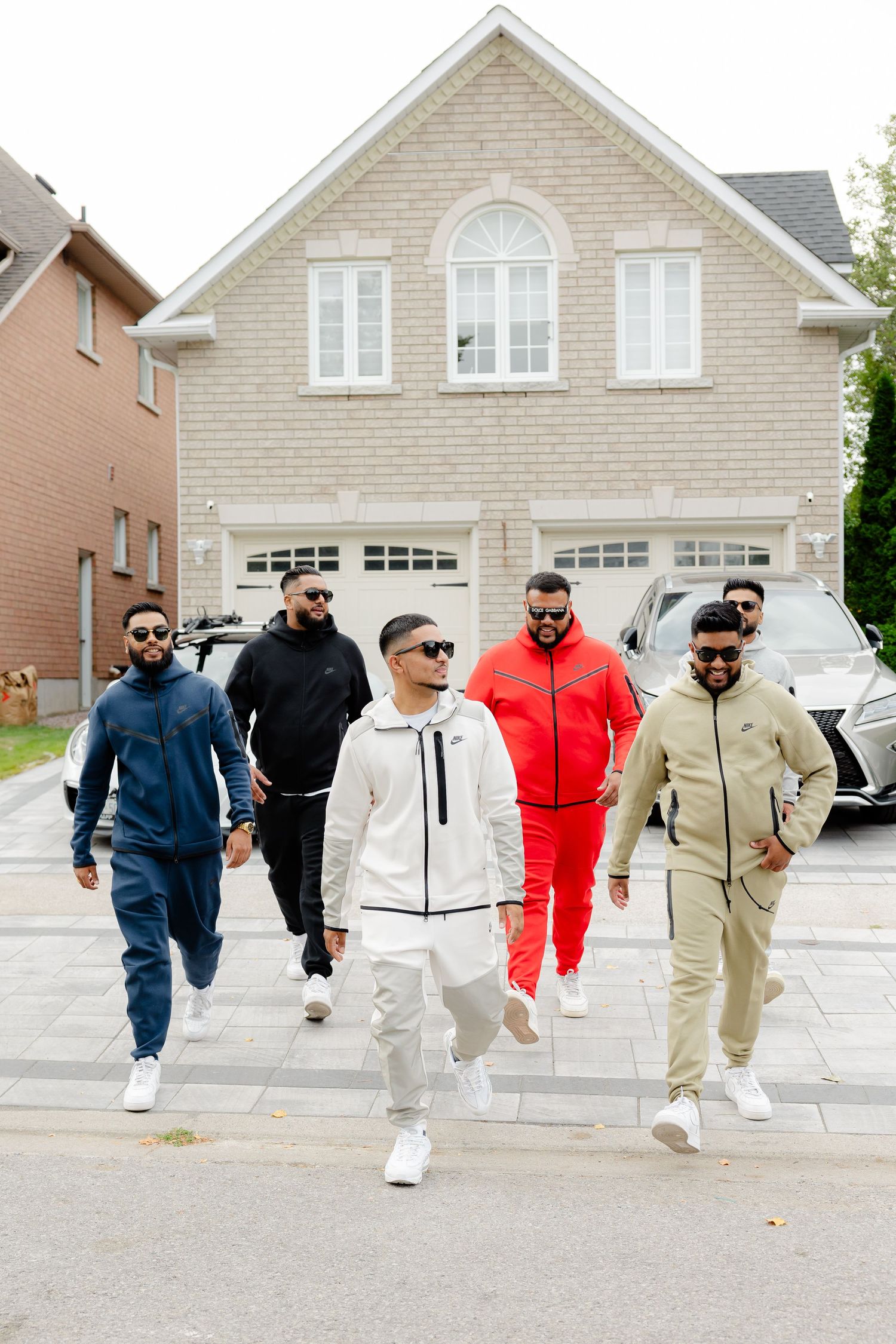 Friends in coordinated sportswear outfits walk together down a residential driveway.