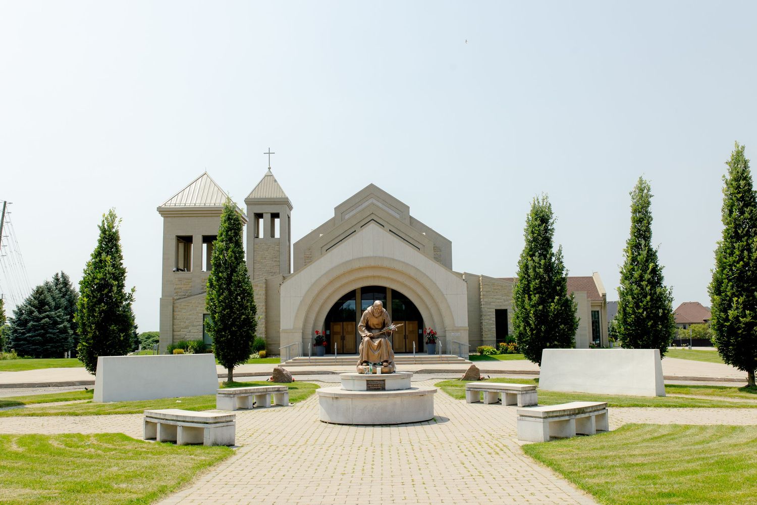 Modern white church exterior with arched entrance and decorative towers against blue sky.