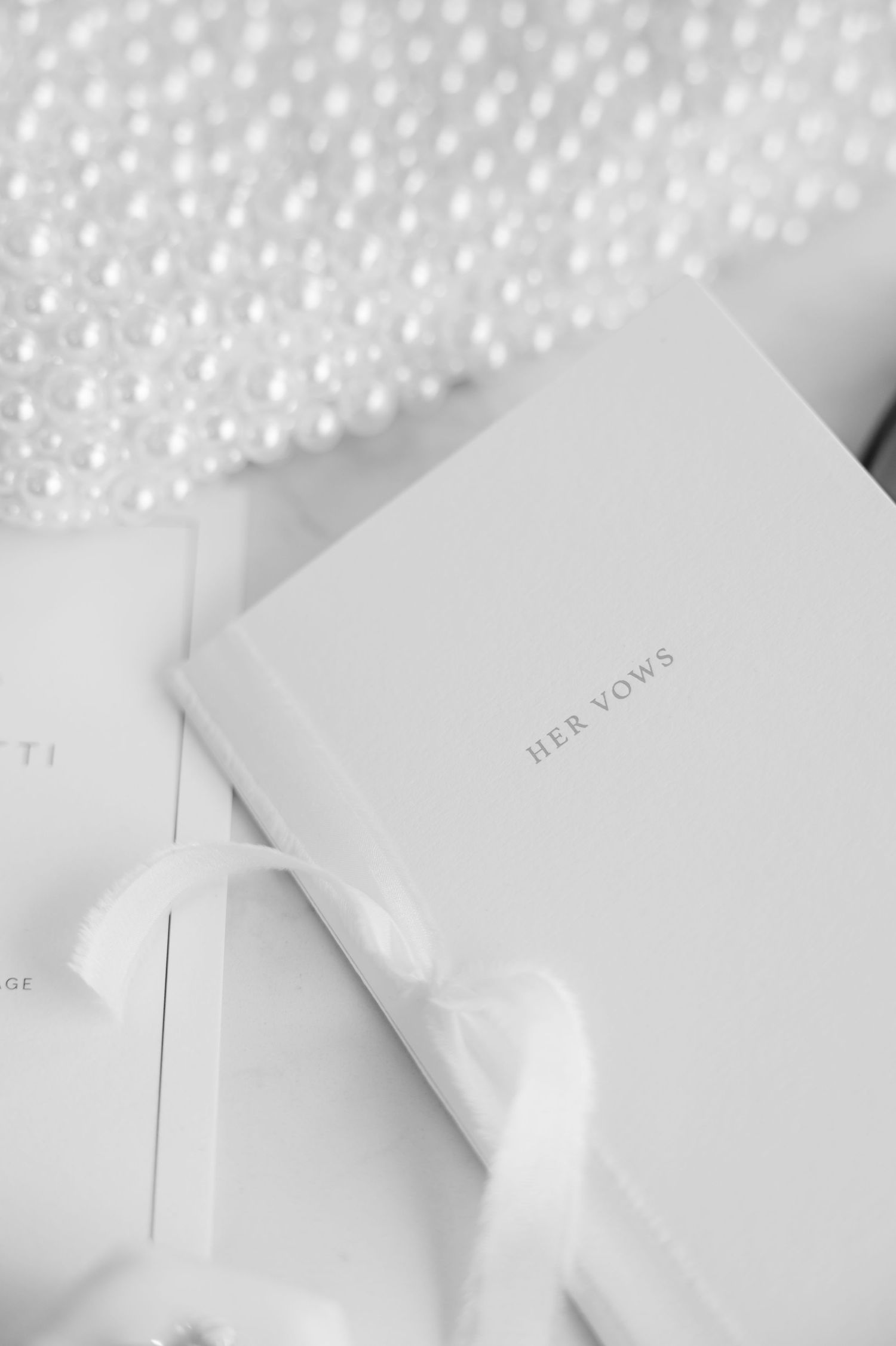 Elegant white book with silver text and pearlescent details in a minimalist wedding setting.