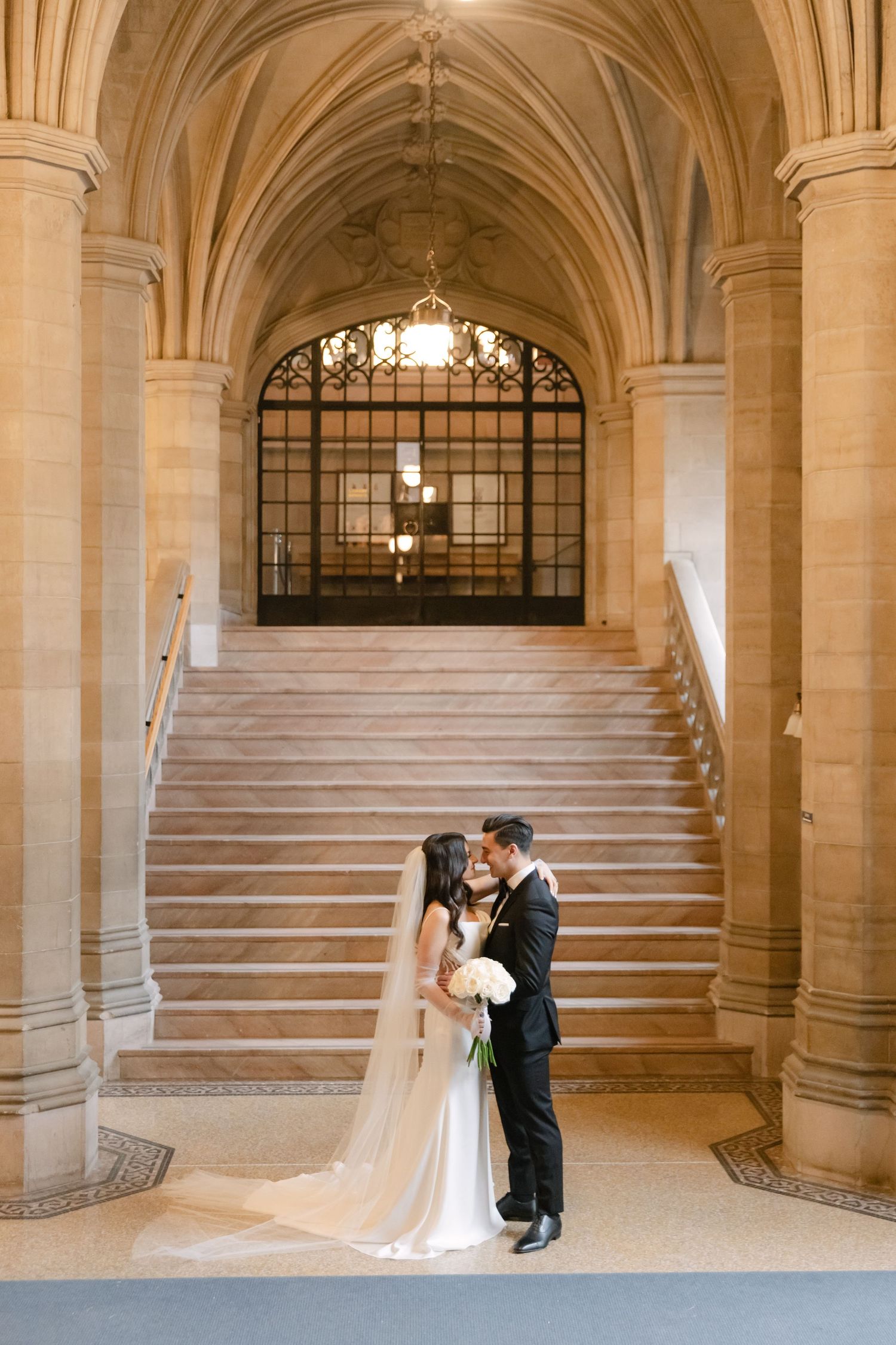 An elegant wedding portrait beneath vaulted gothic arches and stone columns.