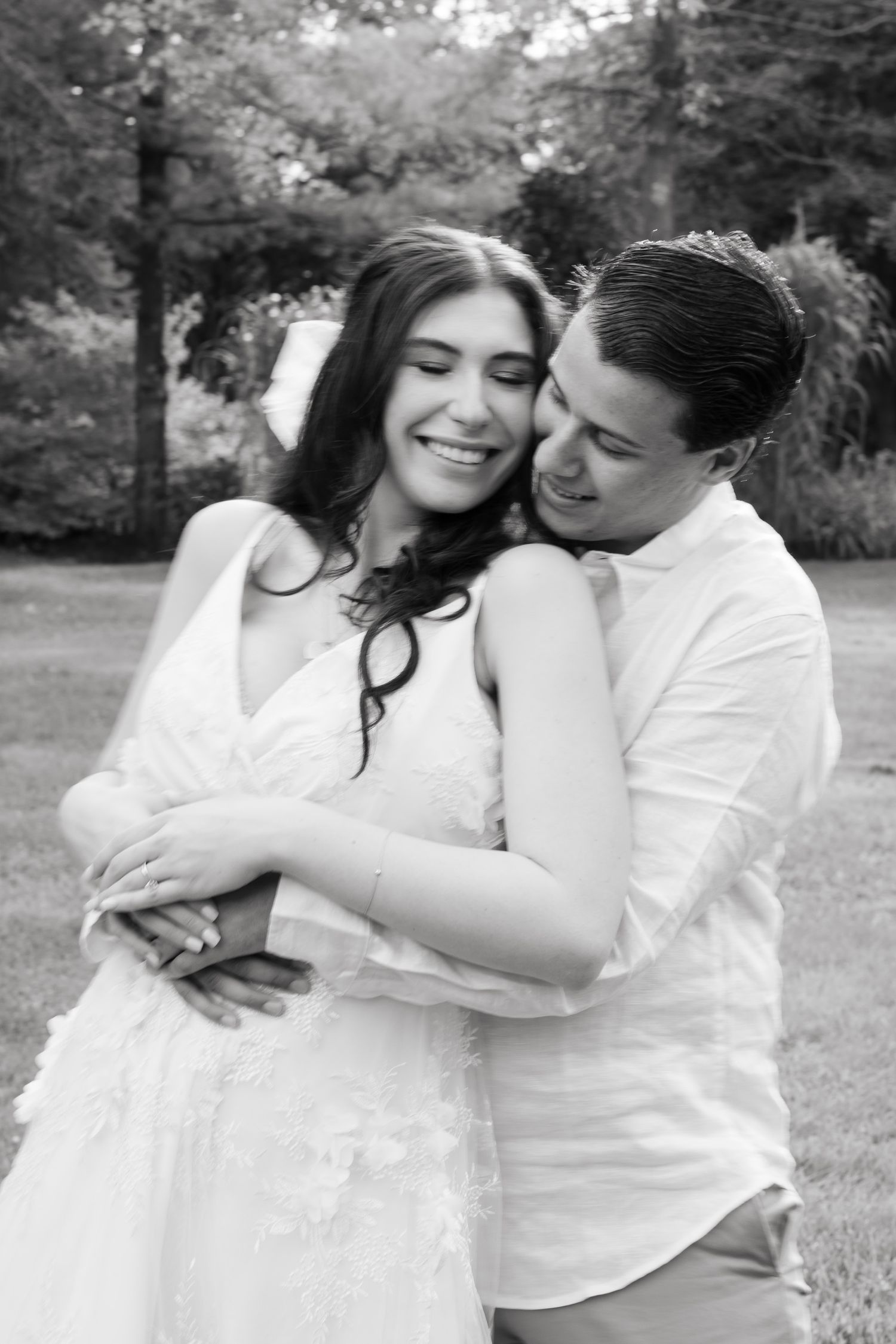 Black and white romantic portrait of couple laughing and embracing in garden setting.