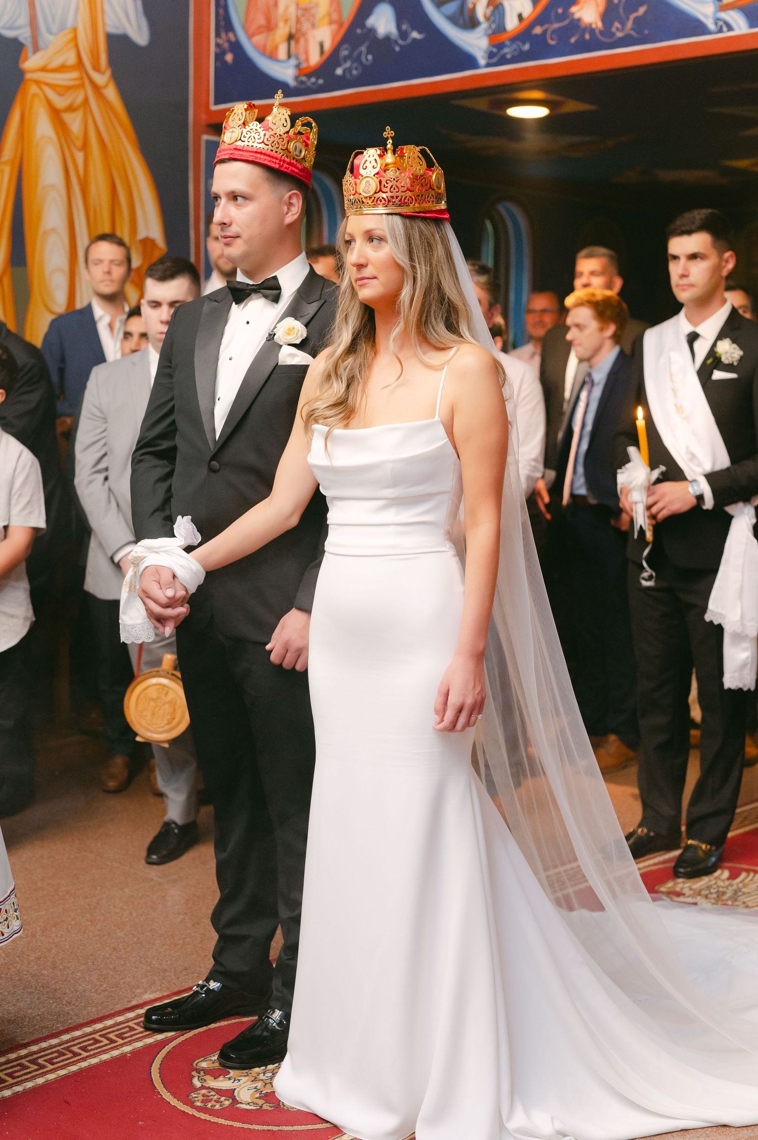 Wedding couple wearing ceremonial crowns during Orthodox Christian marriage ceremony.