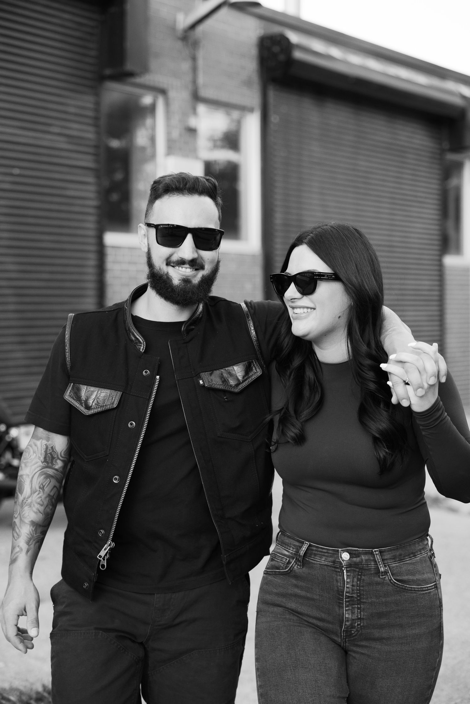 A couple in sunglasses and black clothing sharing a happy moment in black and white photography.