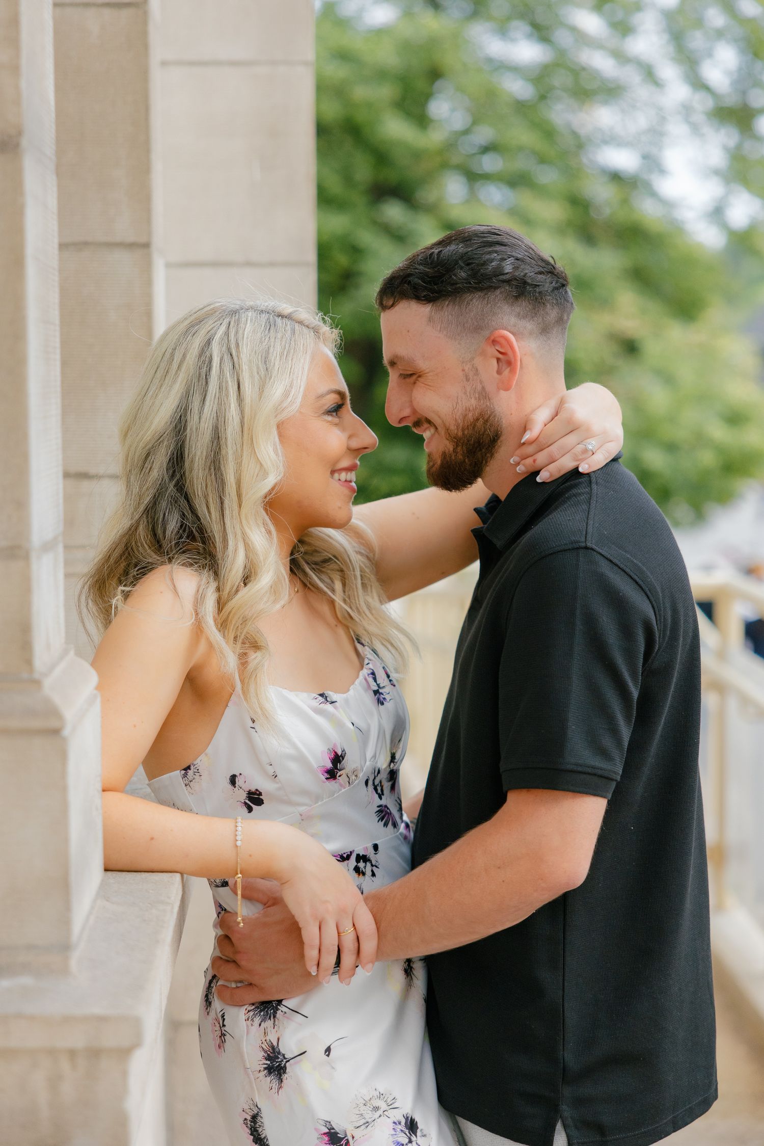 A laughing couple shares a close embrace against classical architecture.