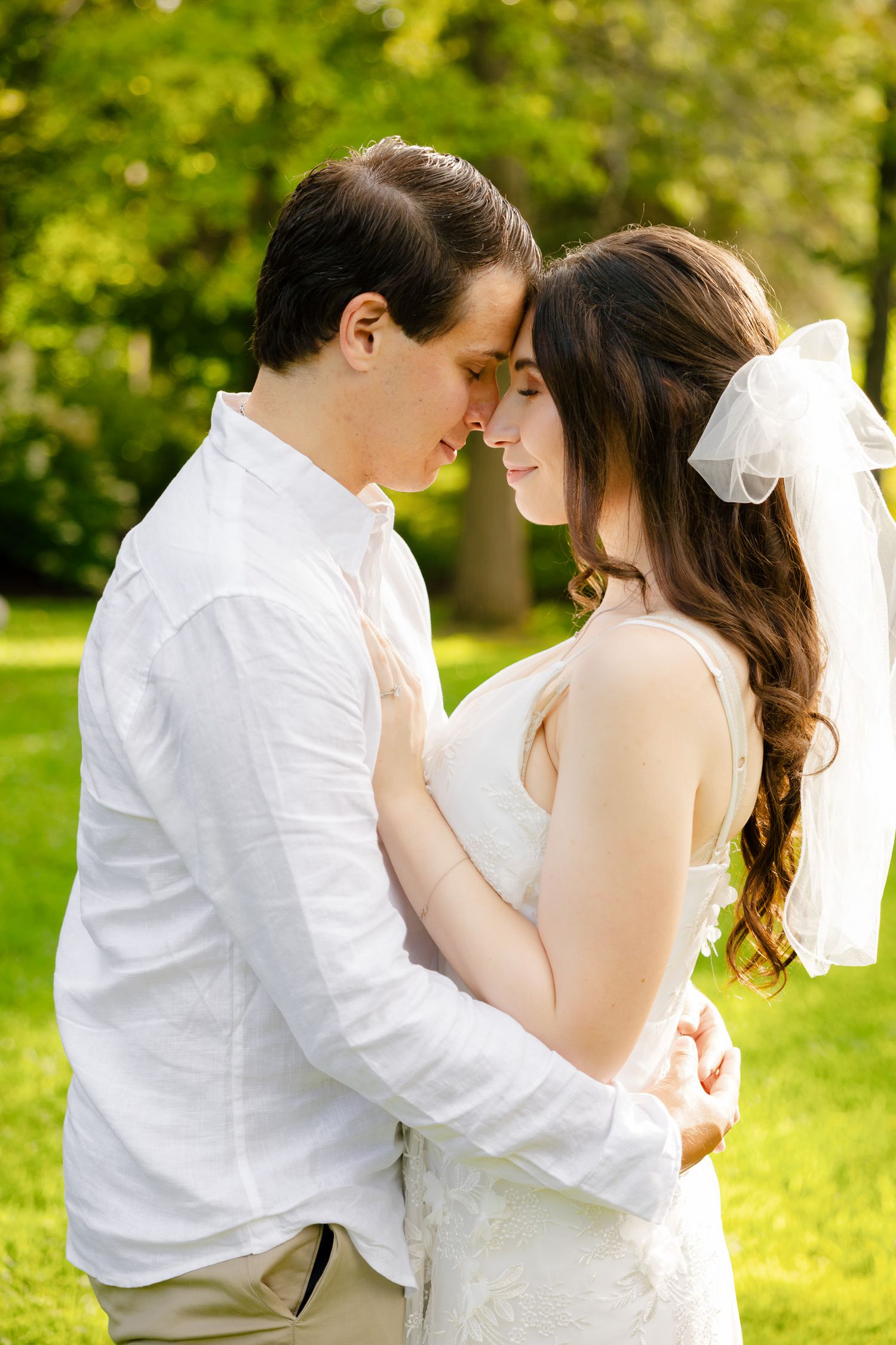 An intimate forehead-to-forehead pose of a couple in their wedding attire.