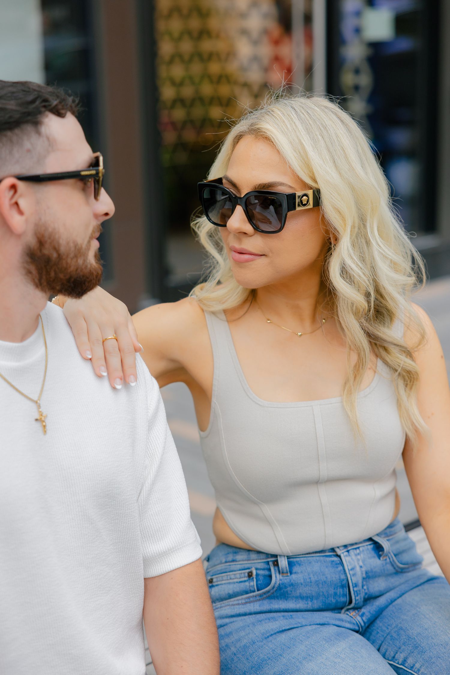 Couple in casual summer outfits sharing an intimate moment on urban bench.