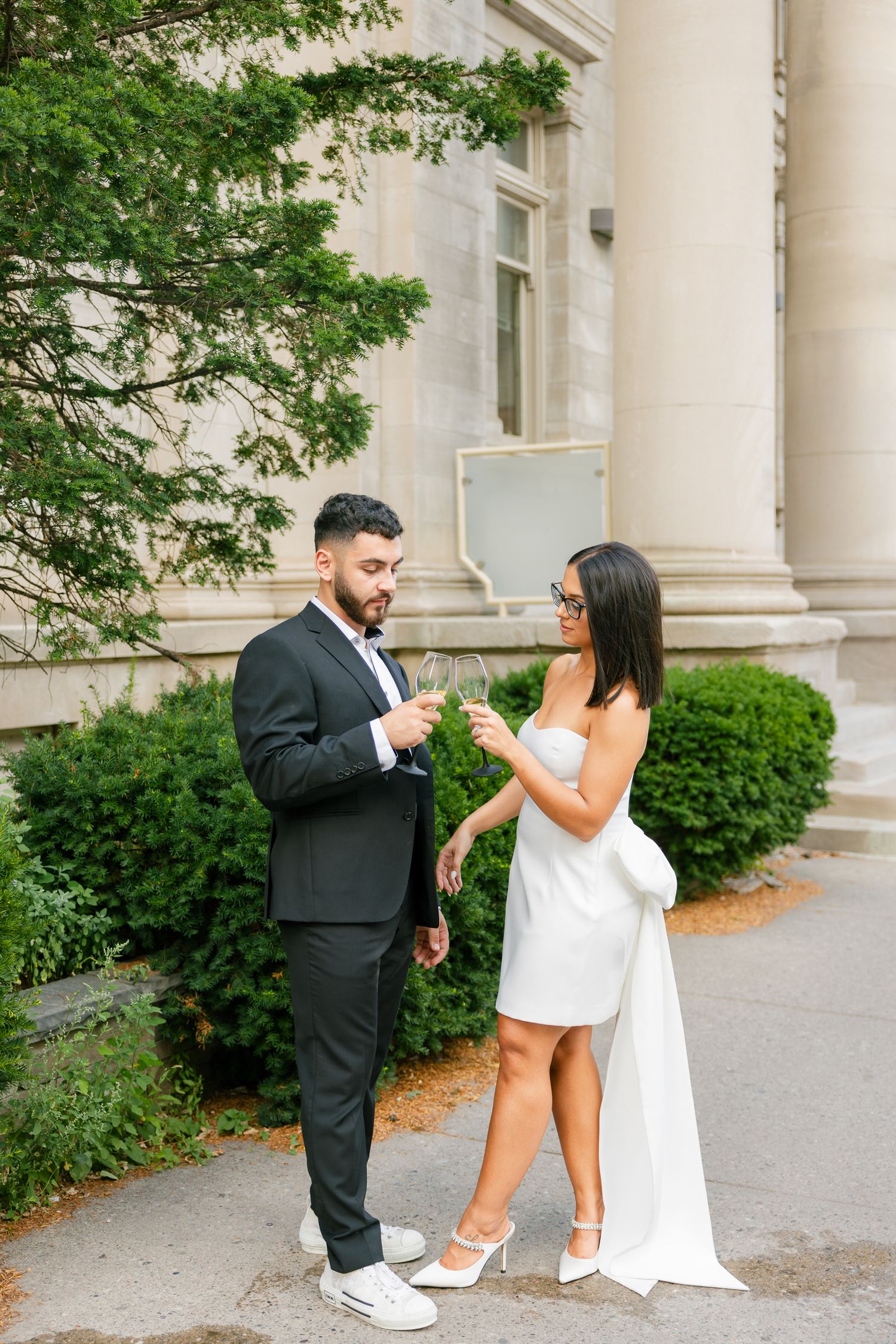Couple in formal attire sharing a moment outside a classic columned building.