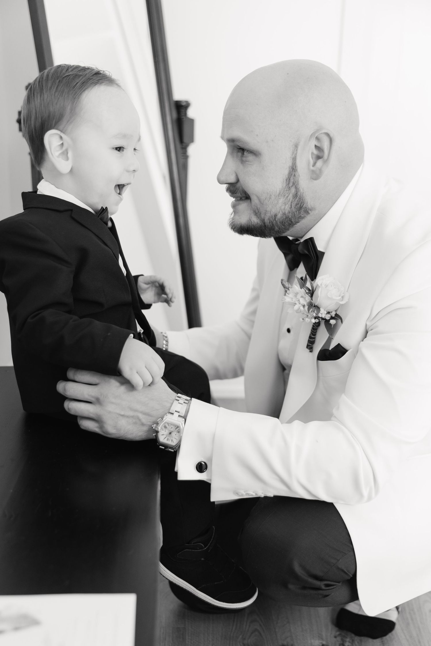 A heartwarming black and white portrait capturing a joyful moment between two in formal attire.