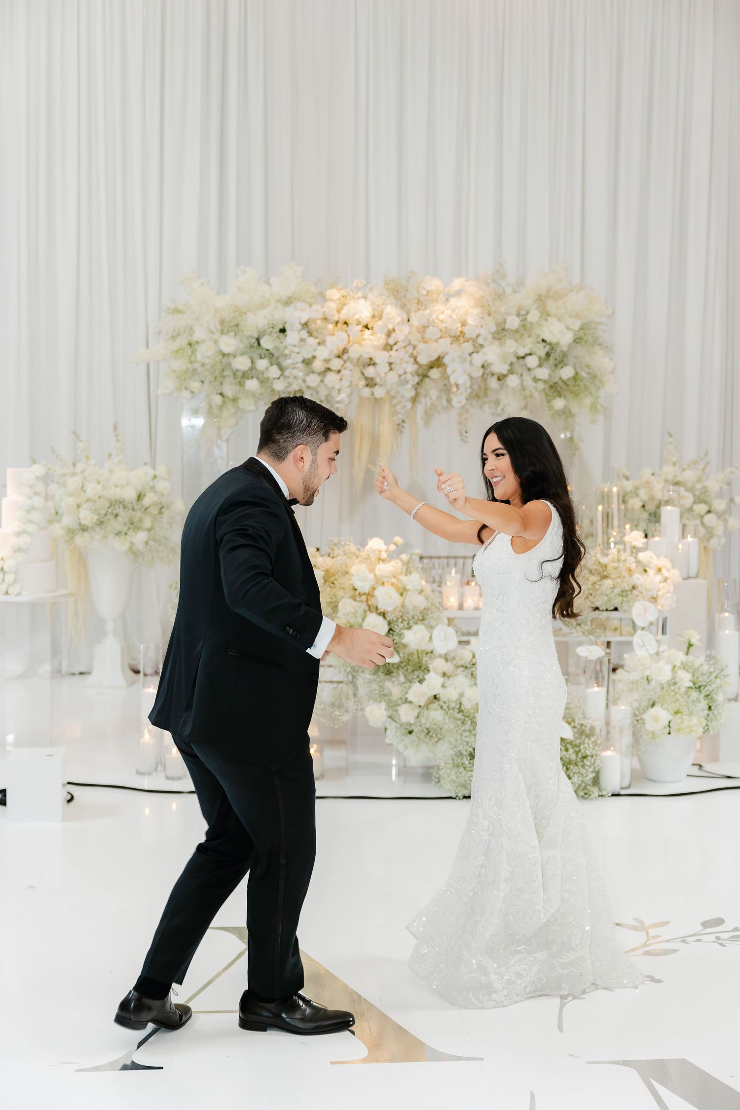 A playful dance moment between newlyweds on their wedding day with white floral decorations.
