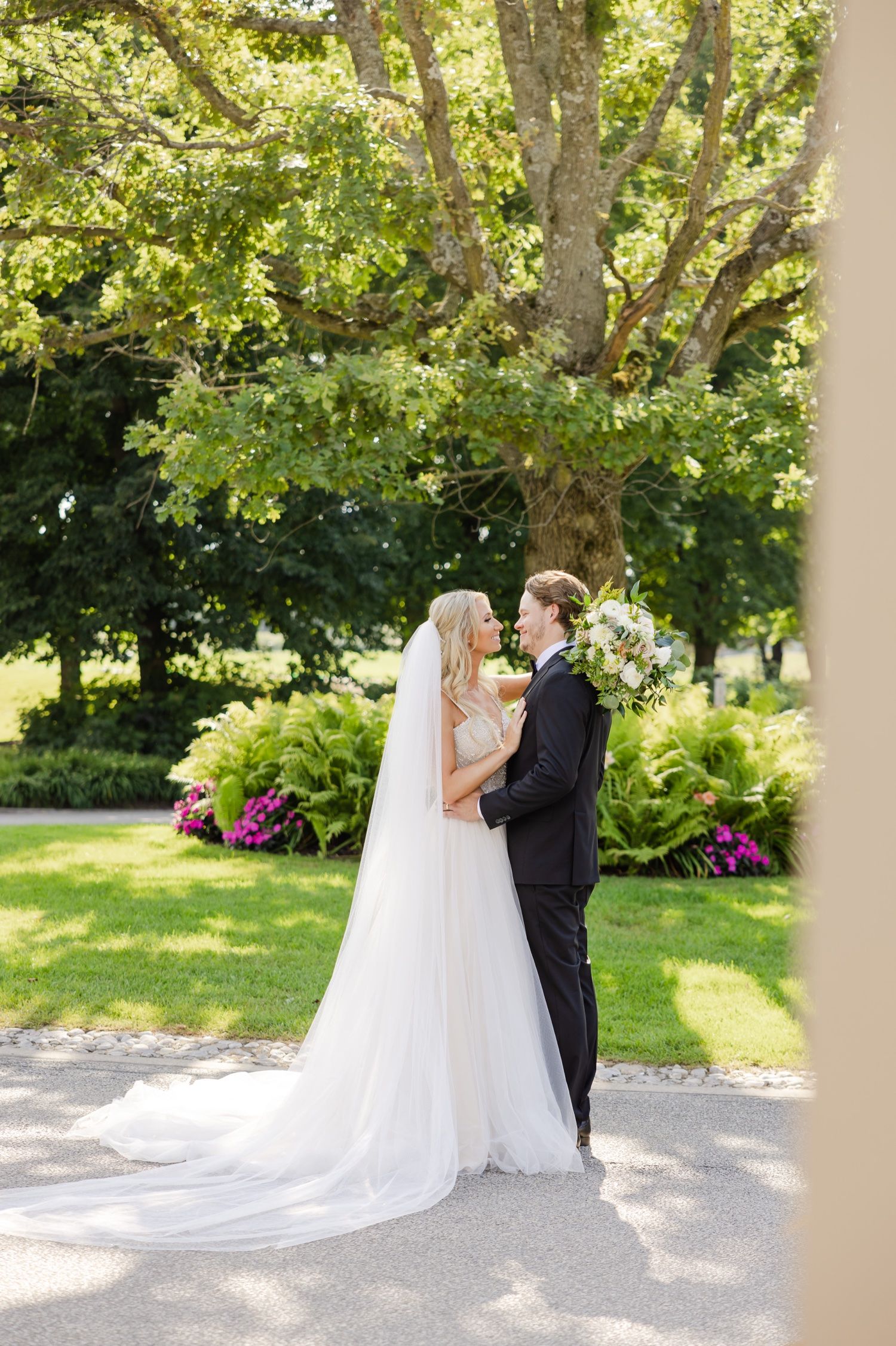 Wedding couple shares an intimate moment in a sunlit garden setting.