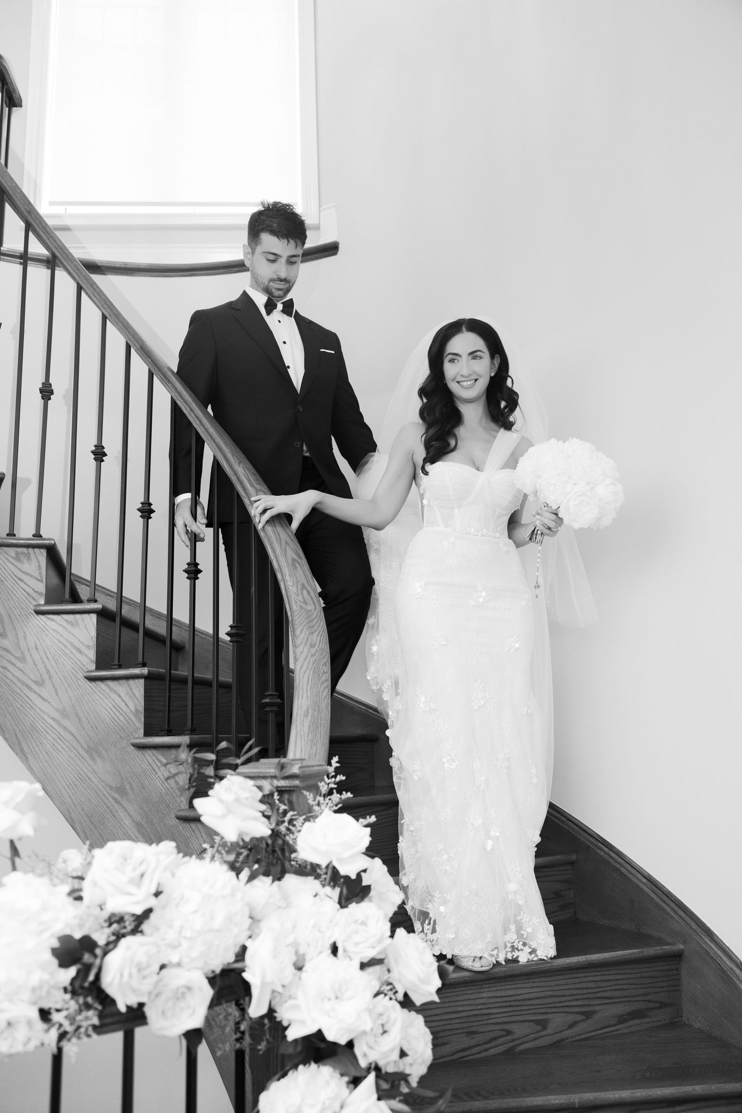 A classic black and white wedding portrait on an elegant staircase decorated with flowers.