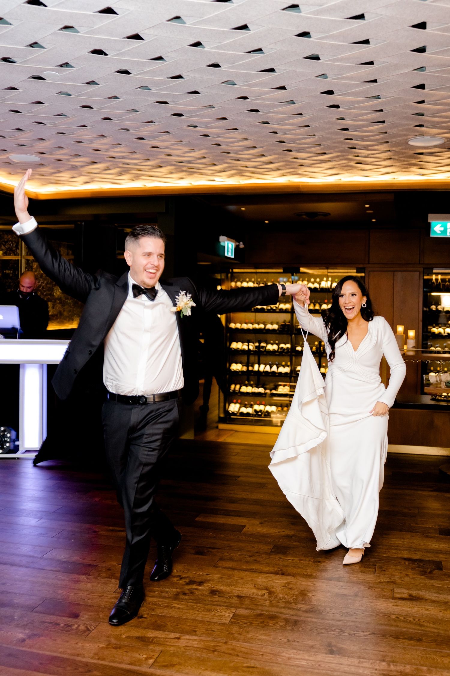 Joyful celebration dance on wooden floor under geometric patterned ceiling with warm lighting.