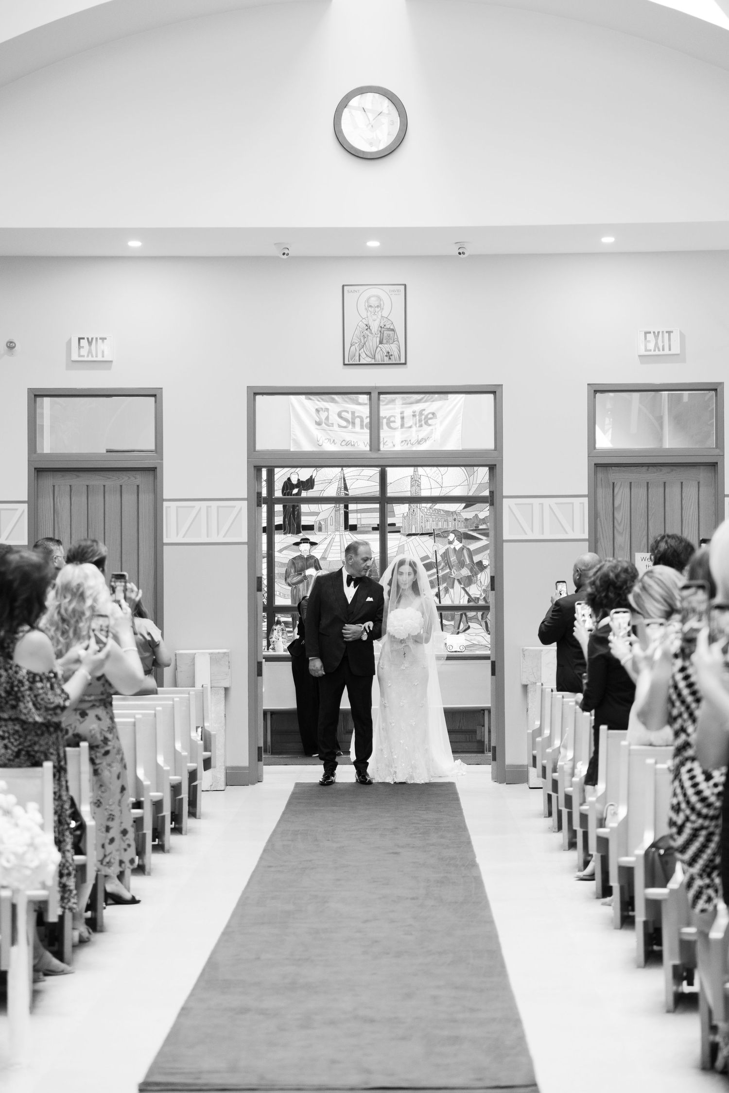 Traditional church wedding ceremony with guests seated in wooden pews along red-carpeted aisle.