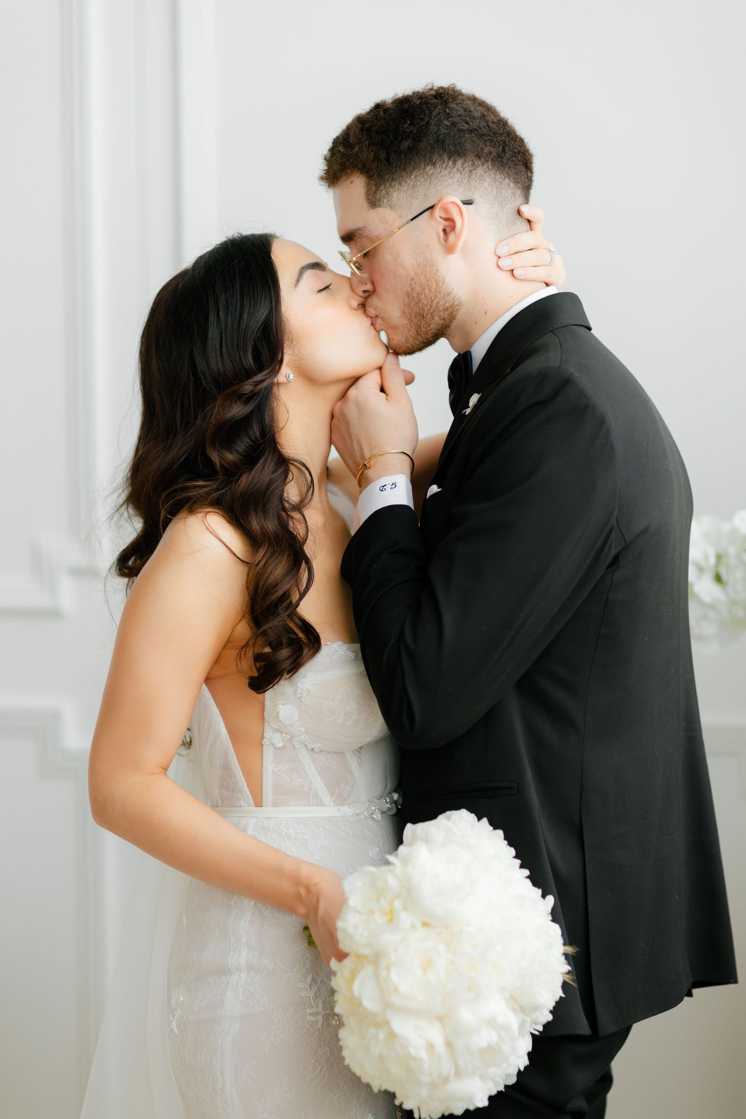 A tender moment captured between newlyweds sharing a kiss in a bright white room.