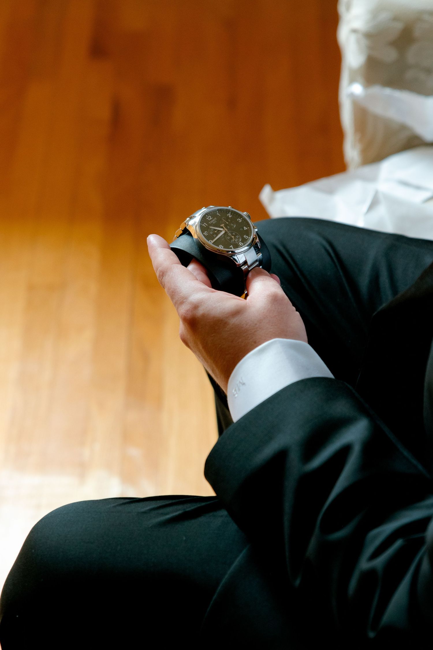 Detail shot of hands holding an elegant watch while dressed in formal attire.