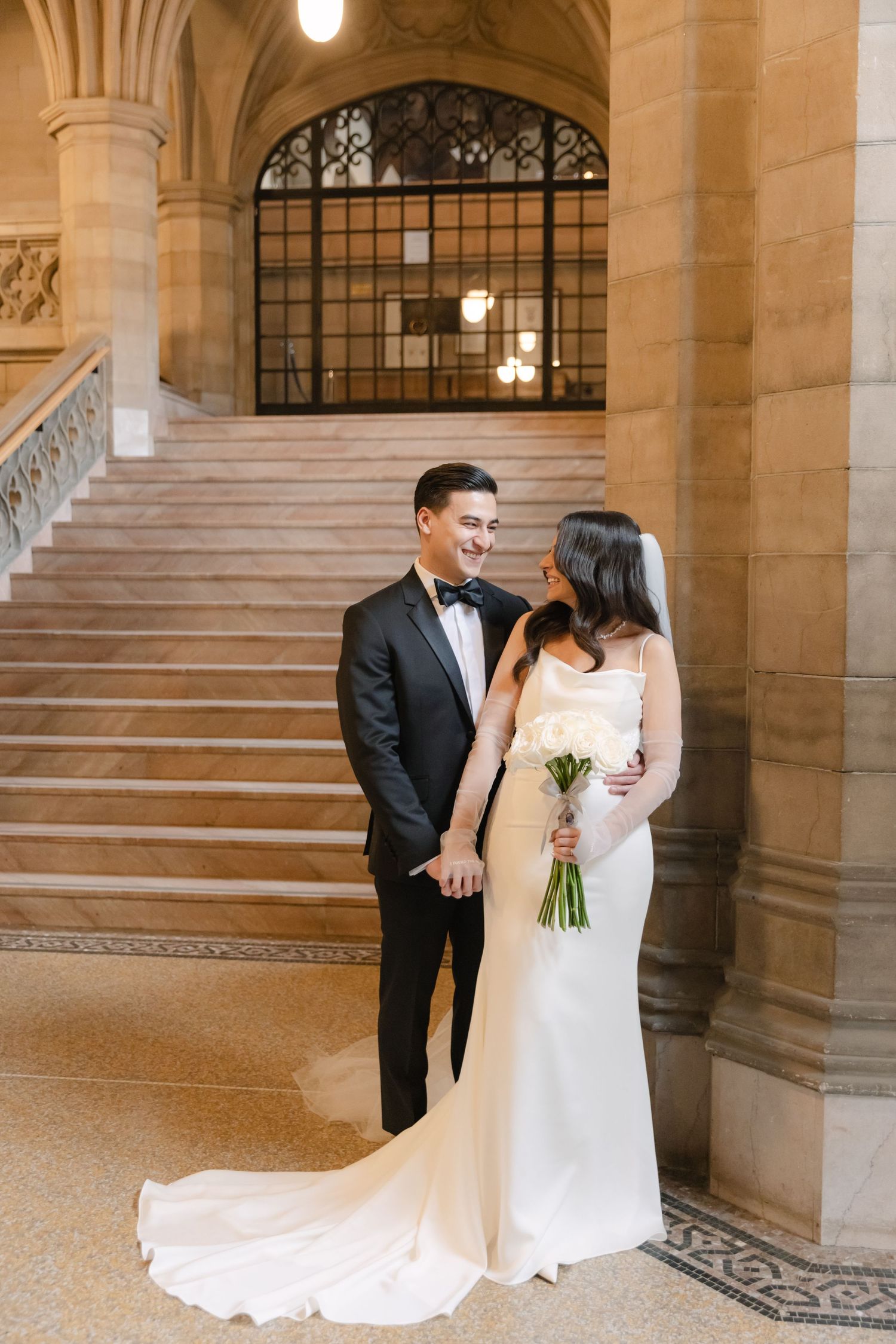 Candid wedding portrait of couple sharing a joyful moment on ornate staircase.