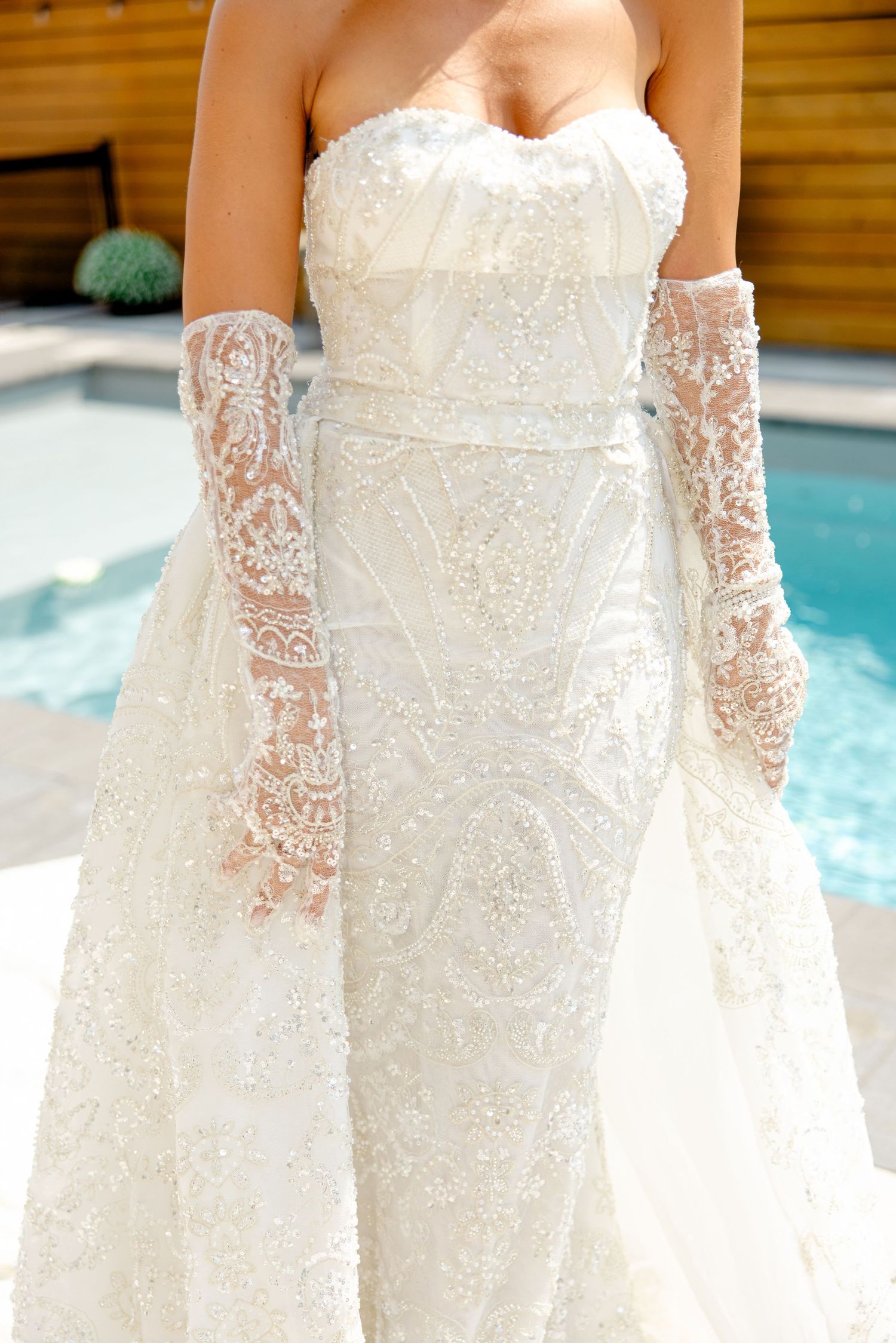 Close-up detail of a white lace wedding dress with sheer embroidered gloves.