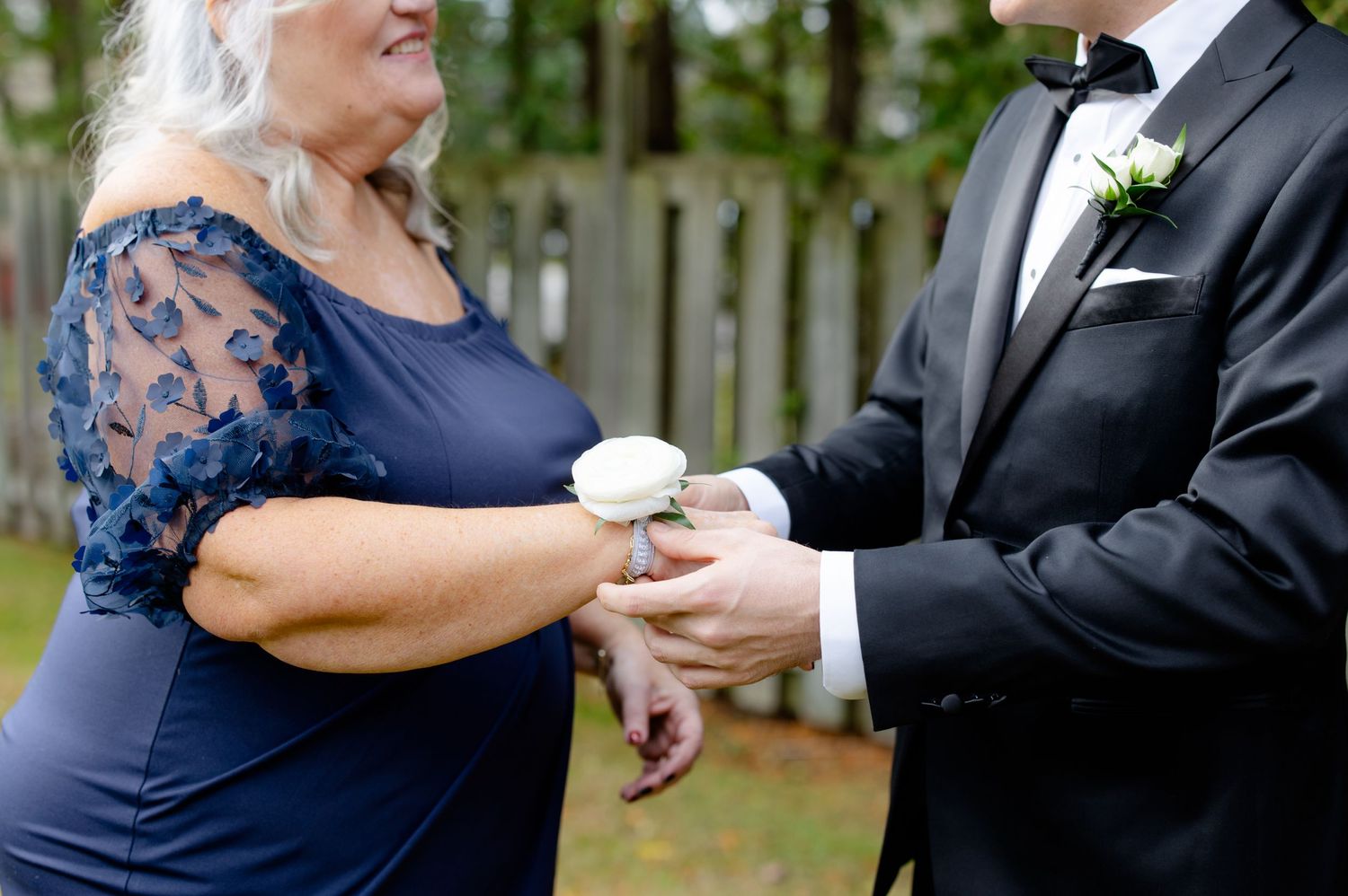A tender moment between two people during a formal occasion in an outdoor garden setting.
