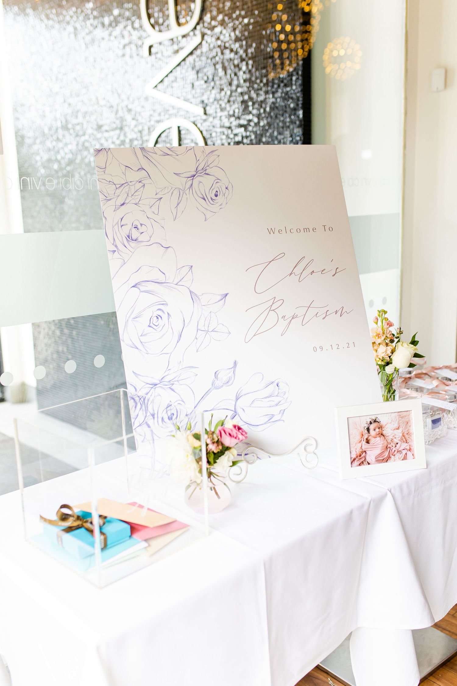 Elegant welcome sign with floral design and calligraphy displayed on a white tablecloth.