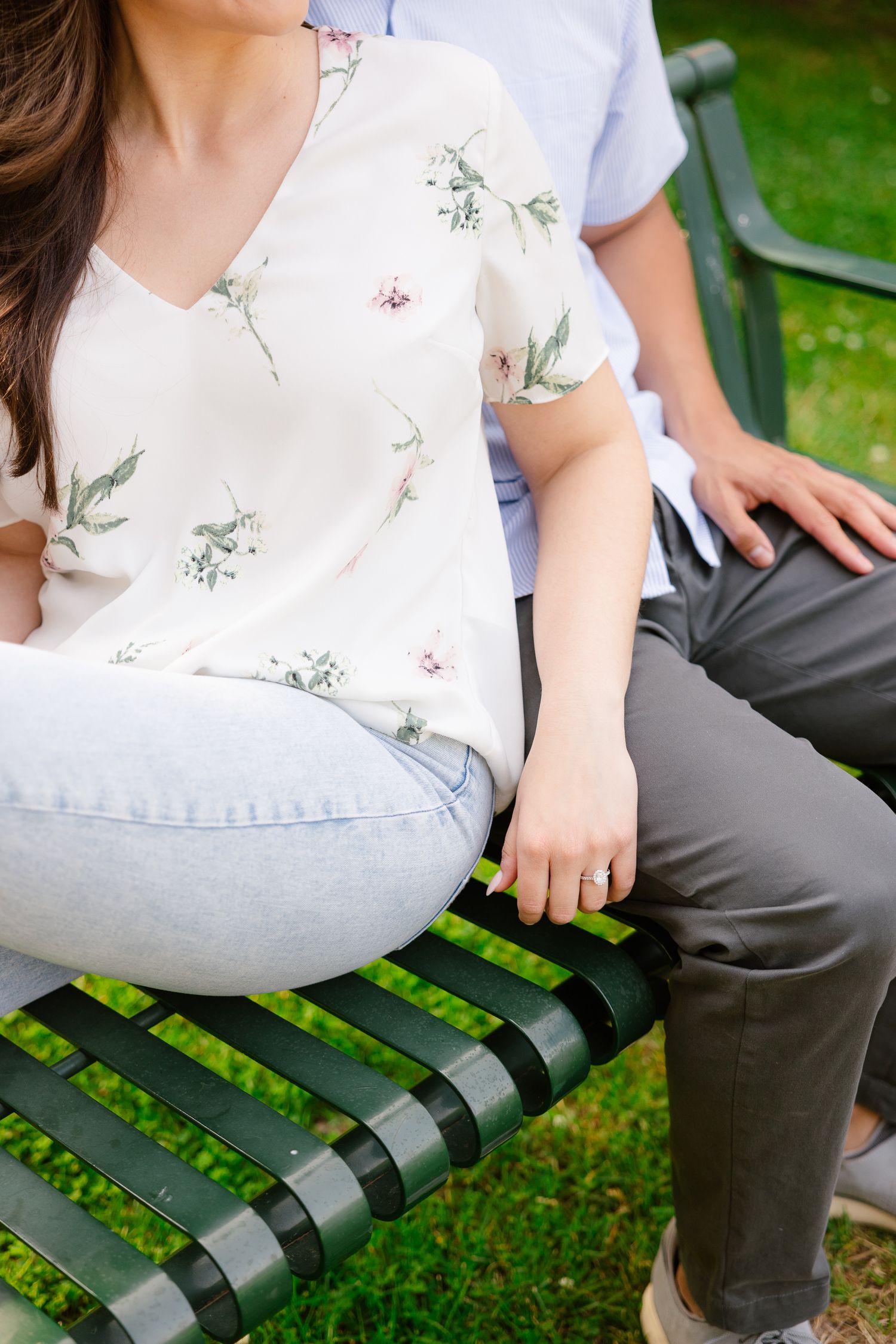 Close-up of a floral print top and casual wear while sitting on a green park bench.