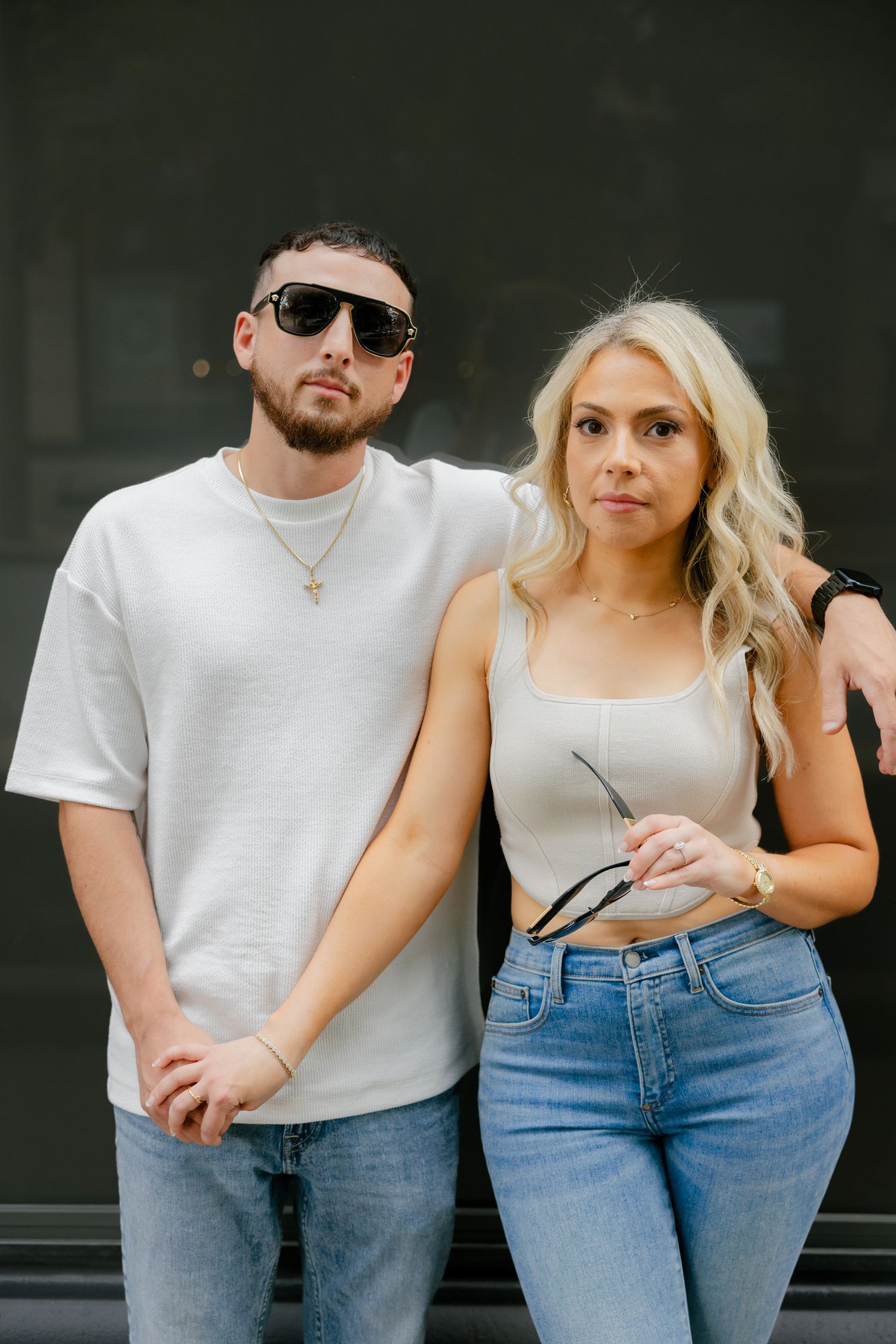 Urban fashion portrait of couple in white and denim against dark background.