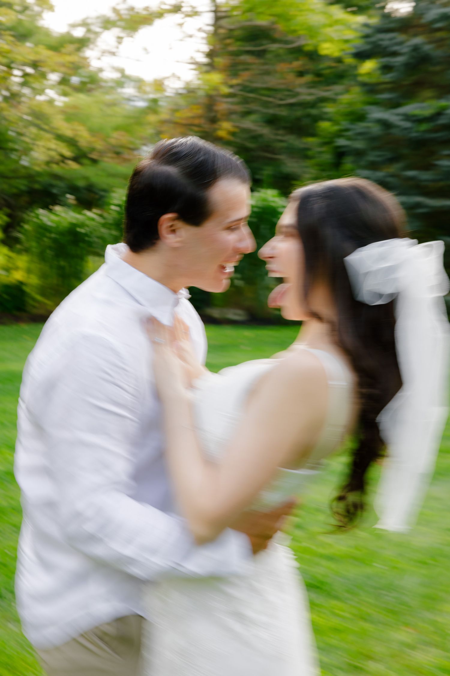 A blurred motion shot capturing a playful dancing moment between a couple in white.