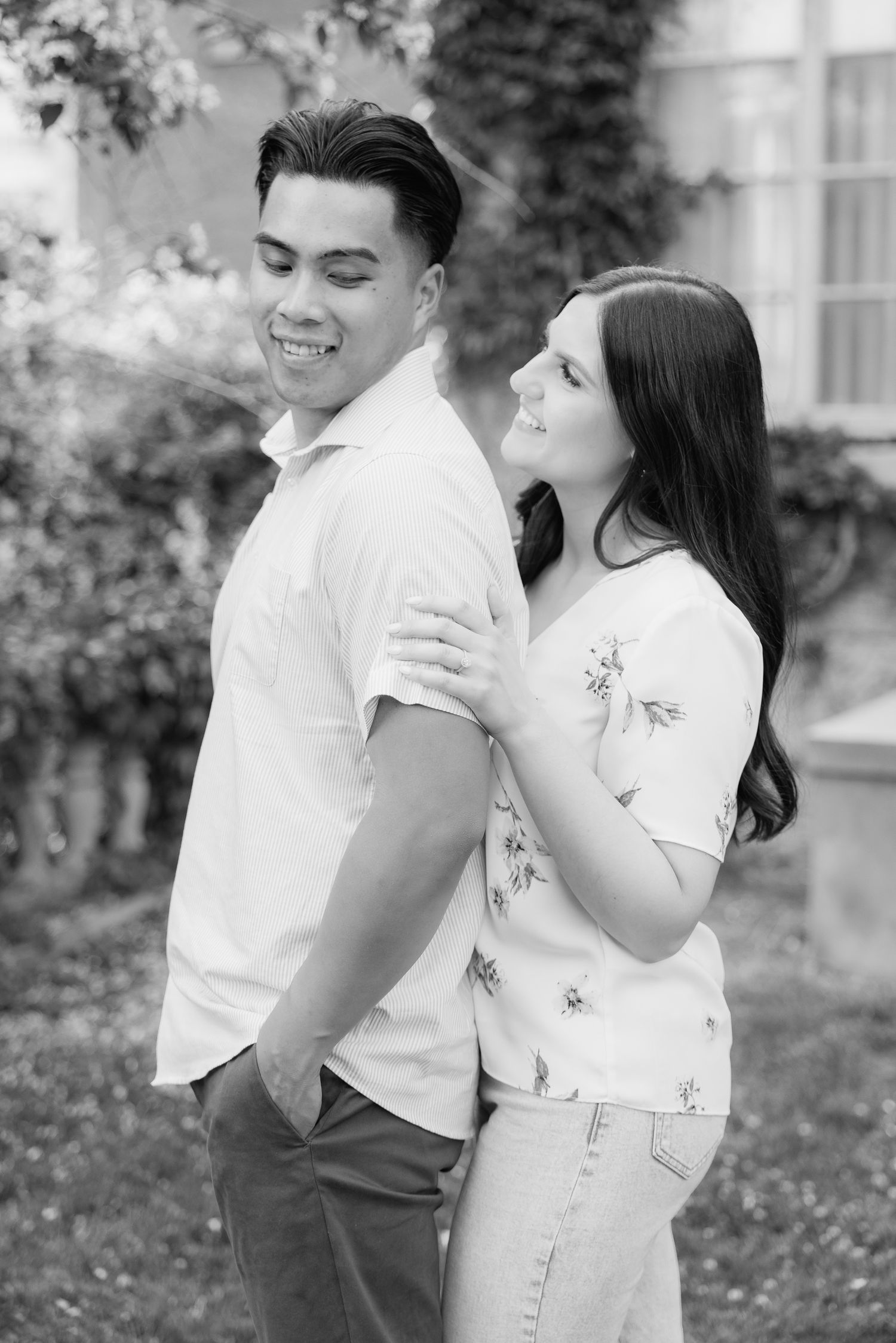 A casual outdoor couple photoshoot showing playful interaction against an ivy-covered wall.