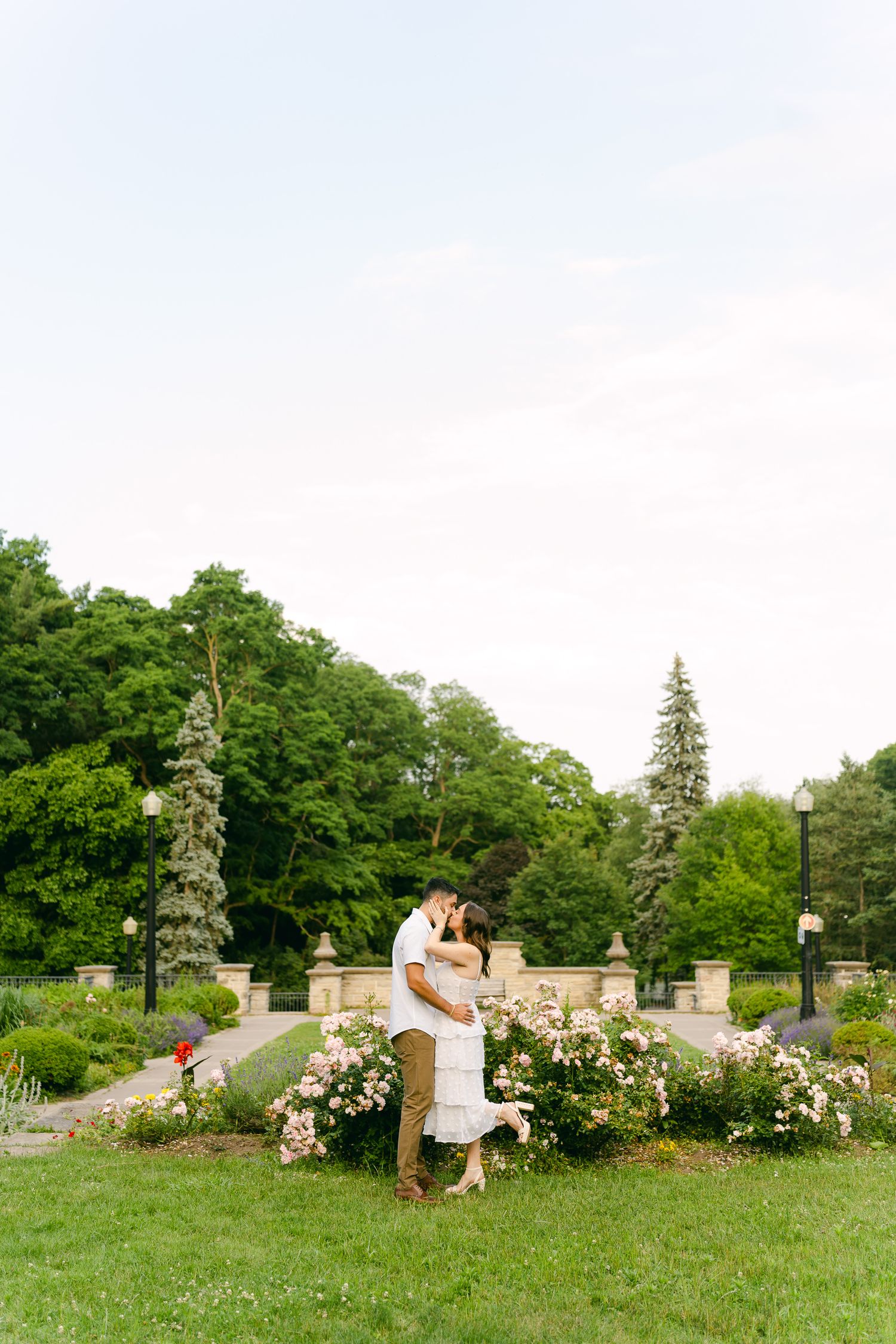 A romantic moment captured in a garden setting with blooming roses and stone architecture.