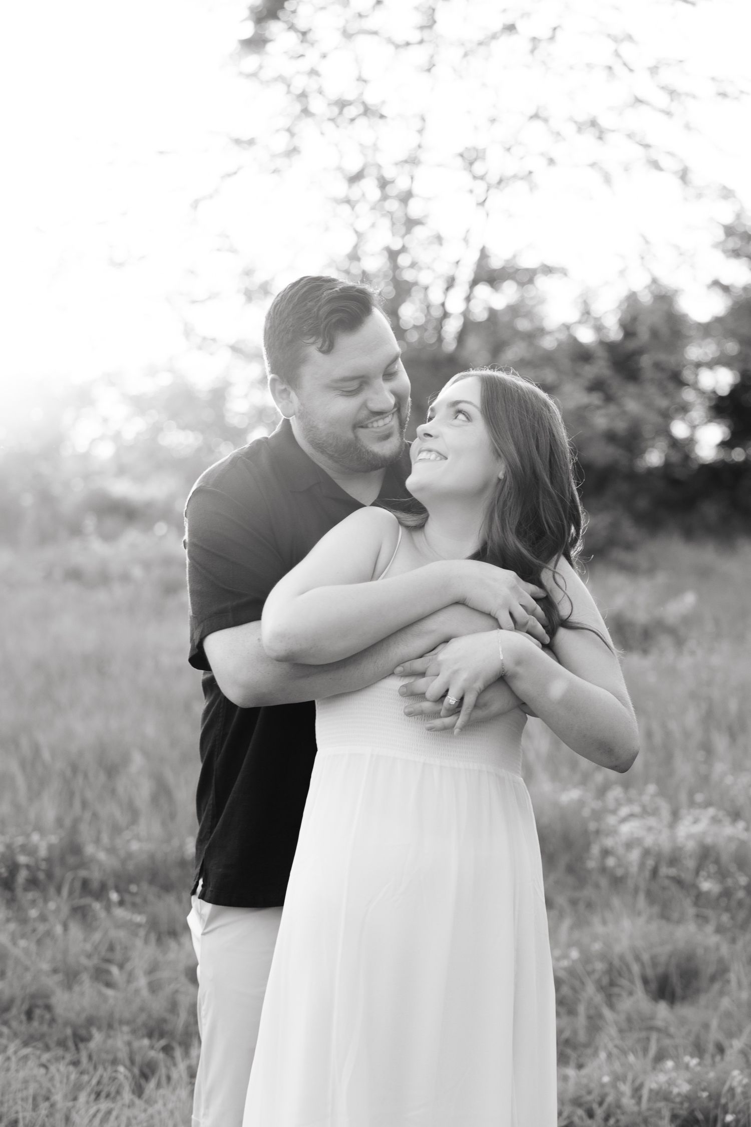 Black and white portrait of couple embracing in outdoor setting.